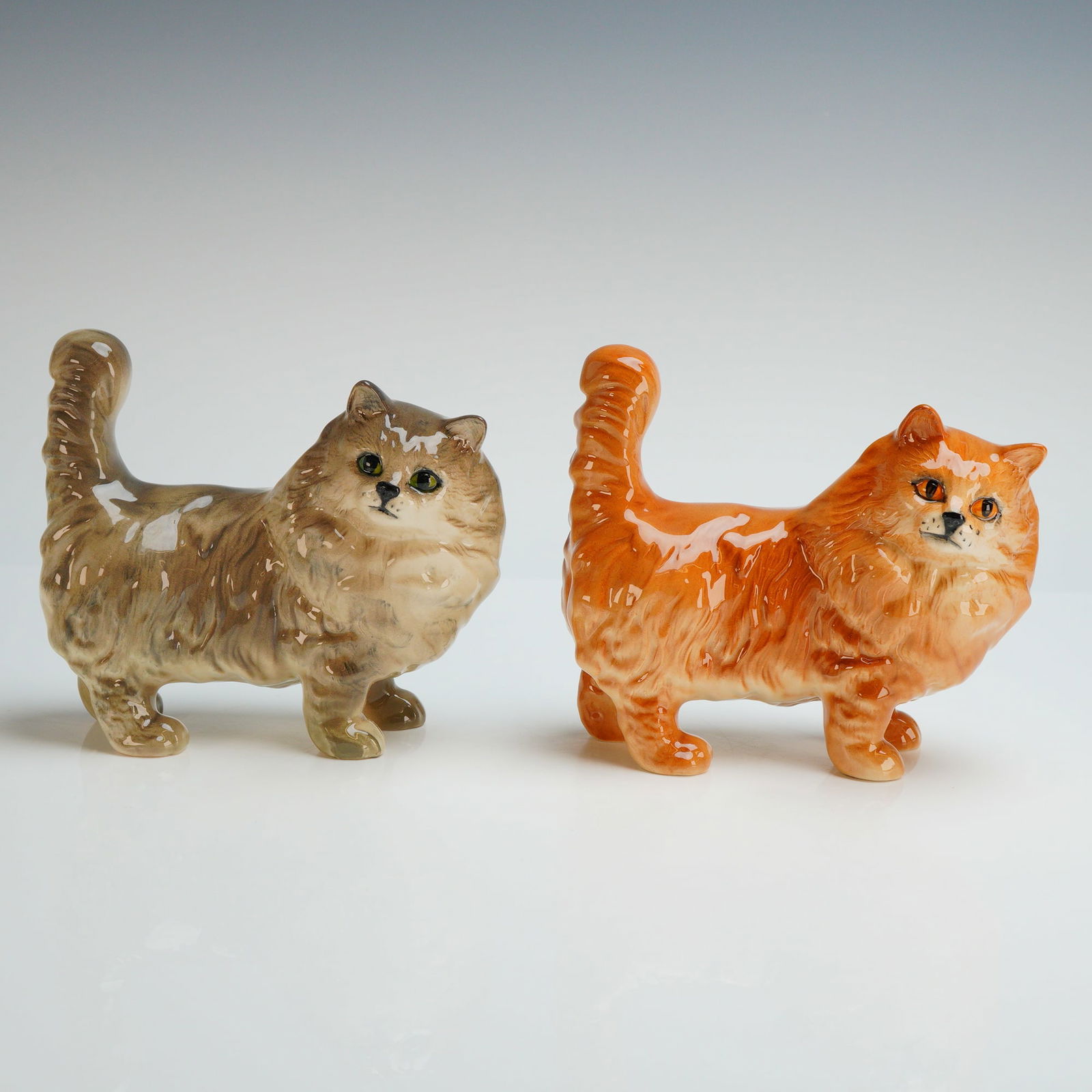 2pc Royal Doulton Persian Cat Figurines: A pair of Royal Doulton glazed ceramic figurines modeled as standing Persian cats. Both cats are the same size and feature textured detailing to represent long fur under a high-gloss glaze. One figuri