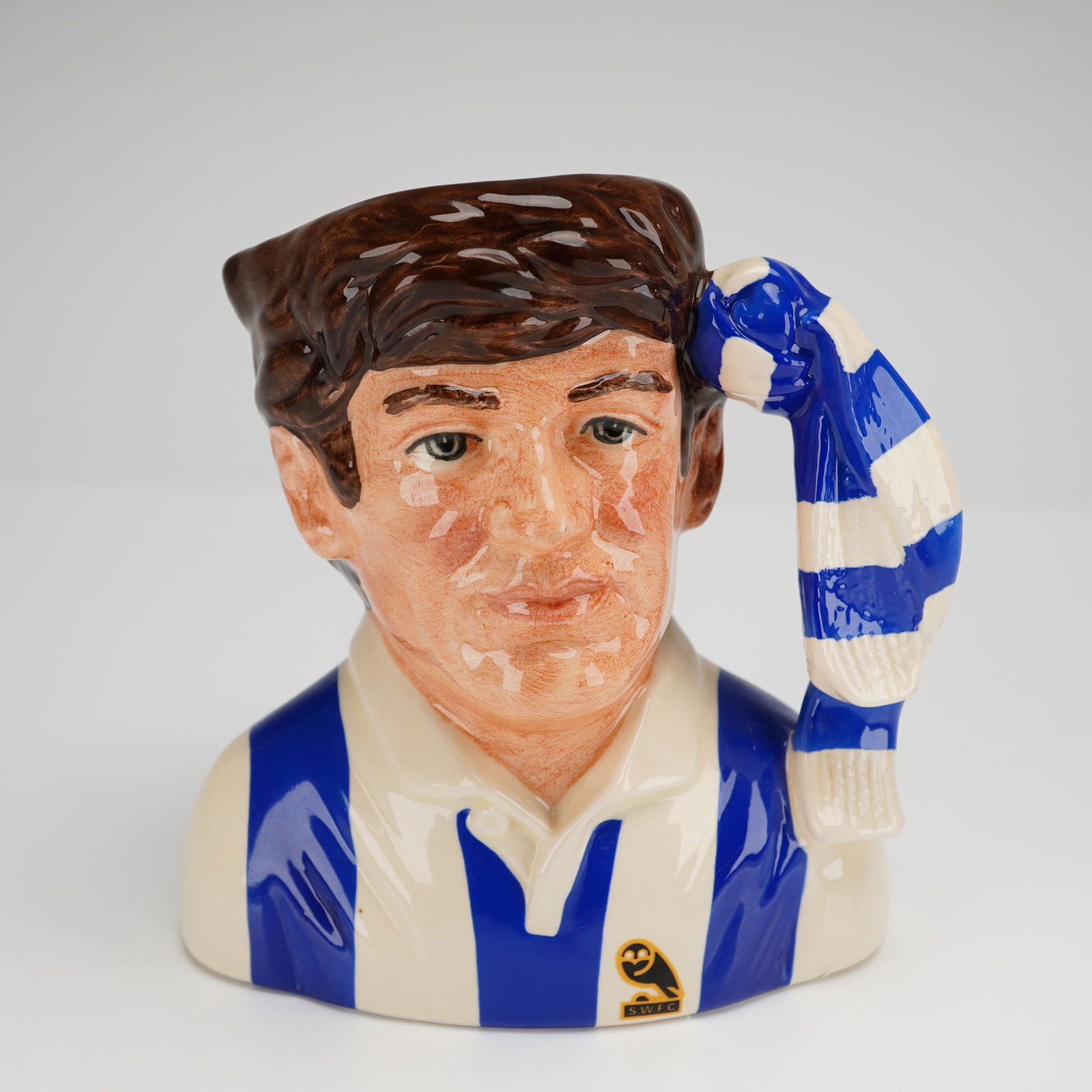 Sheffield Wednesday D6958 Small Royal Doulton Character Jug: A Royal Doulton glazed ceramic character jug from the Football Supporter's series, titled Sheffield Wednesday, model number D 6958. The piece depicts a male supporter with brown hair wearing the club'