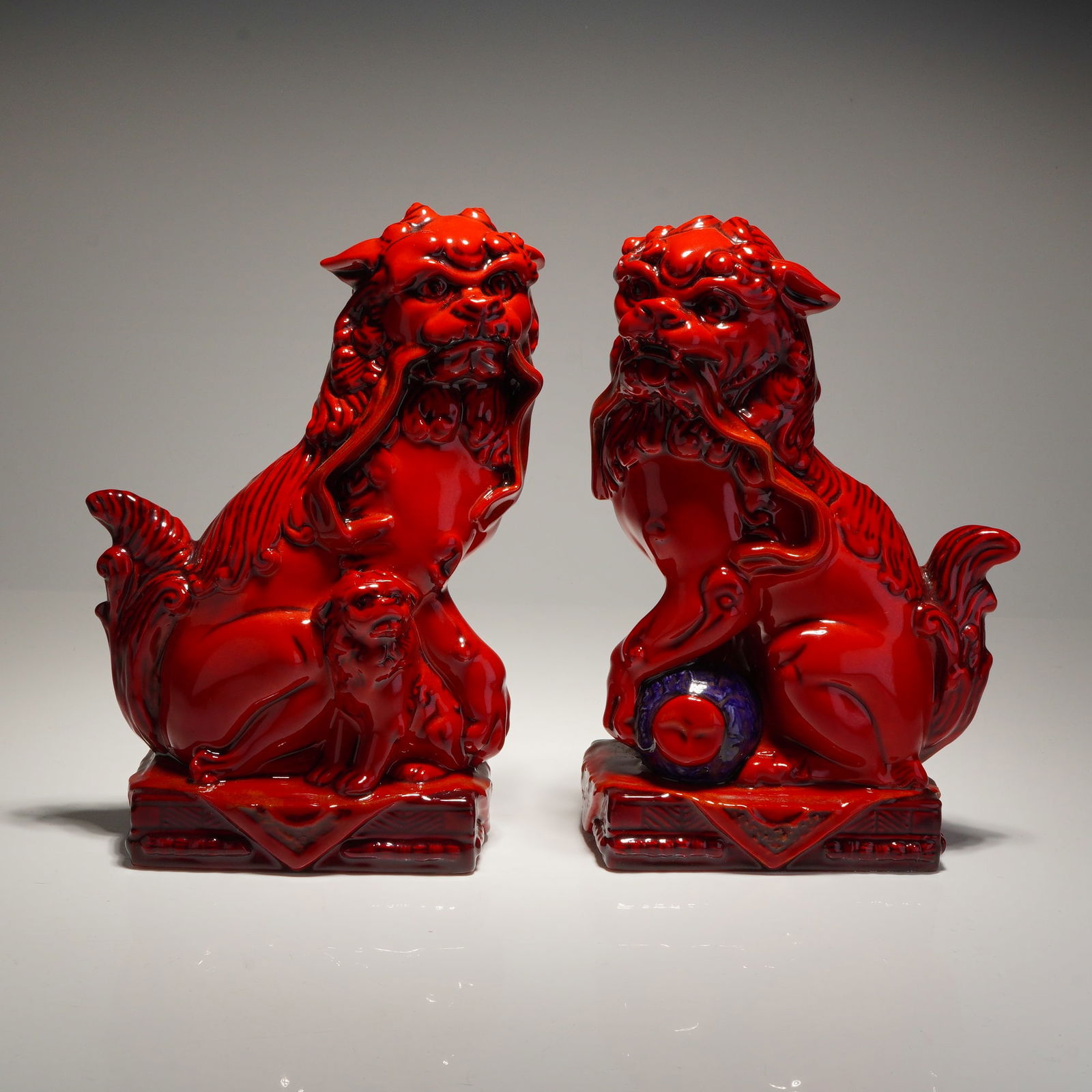 Pair of Royal Doulton Flambe Limited-edition Qinghai Fu Dogs BA34 & BA35: A pair of Royal Doulton porcelain figurines from the Archives Burslem Artwares collection, identified as the Qinghai Fu Dogs. The figures are finished in a high-gloss red Flambe glaze. The set include
