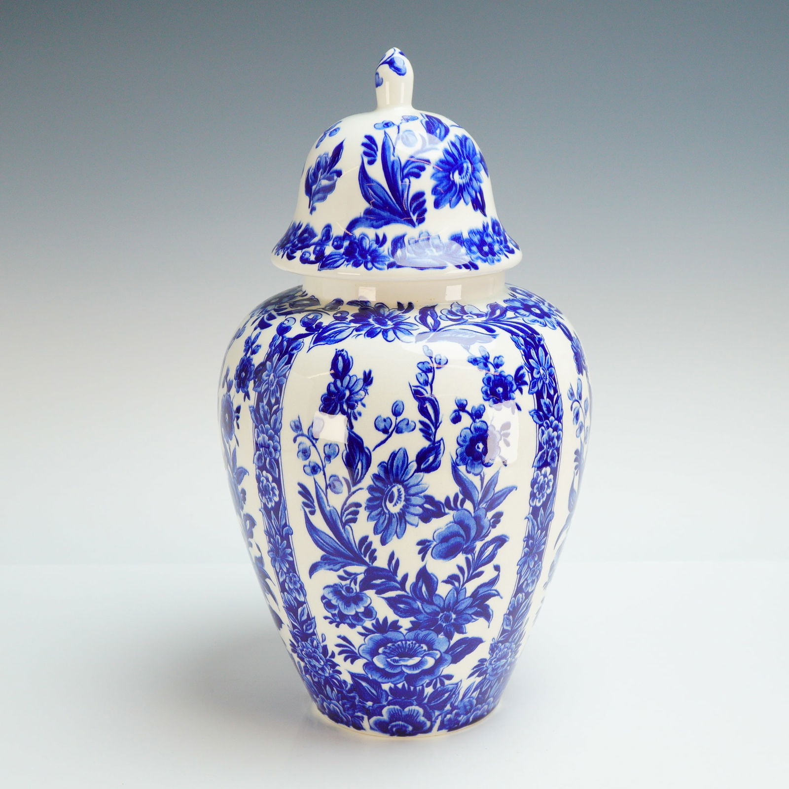 Dutch Delft Blue Porcelain Lidded Jar: A mid-century Dutch Delft blue porcelain lidded jar of baluster form featuring hand-painted floral and foliate motifs arranged in vertical panels. The vessel is accompanied by a matching domed lid