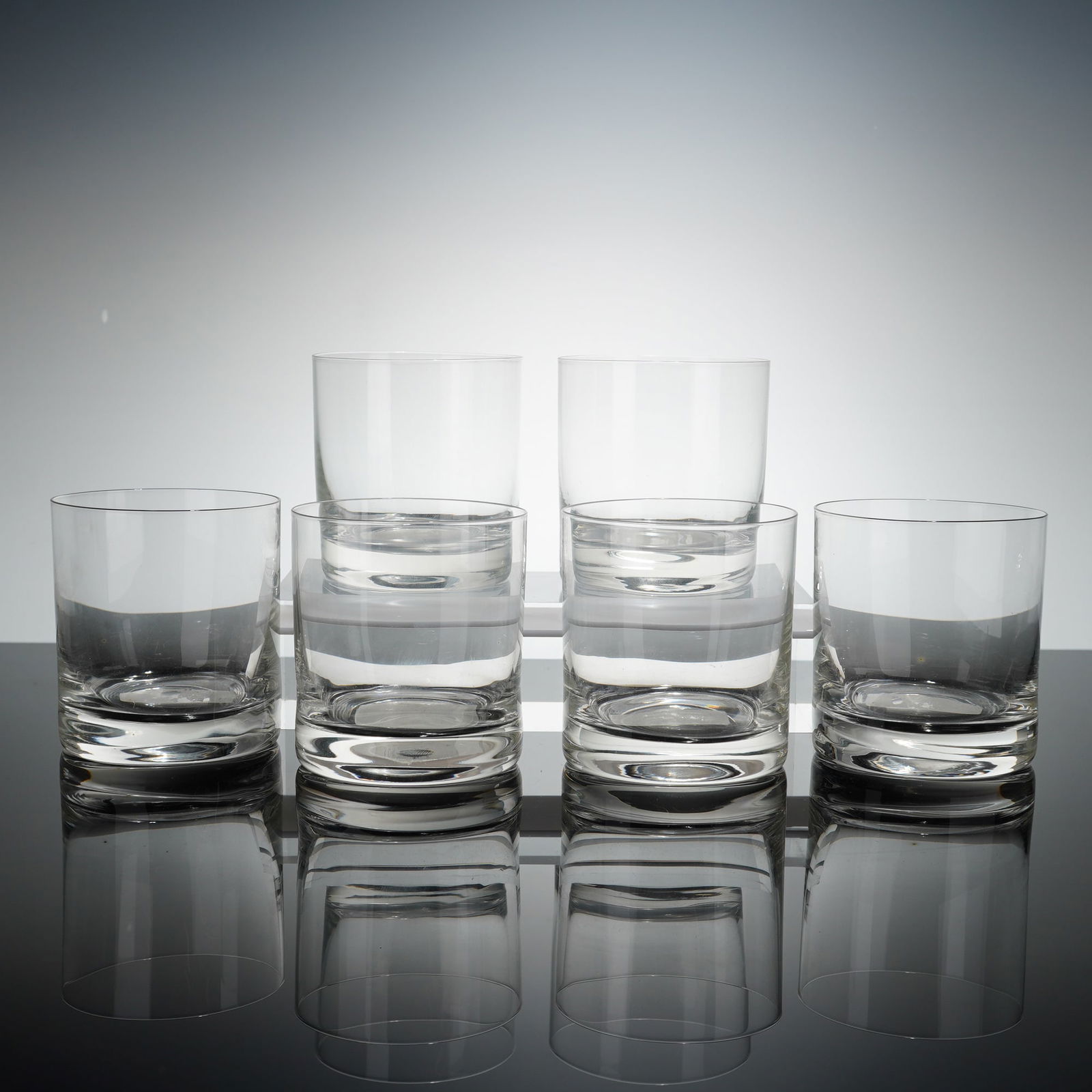 Set of Six Clear Crystal Bourbon Glasses: A set of six crystal bourbon glasses of minimalist, modern design. Each vessel is characterized by a straight-sided, cylindrical form and a substantial, weighted base. The glass is clean and