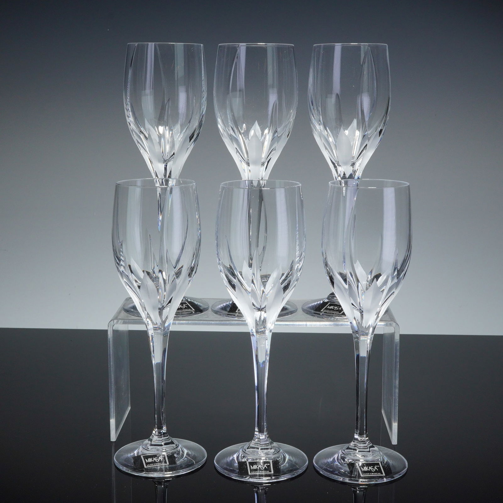 6pc Mikasa Crystal Wine Glasses, Flame D'Amore: This set of six Mikasa lead crystal wine glasses is in the Flame D'Amore pattern. Each glass is designed with a tulip-shaped bowl featuring a frosted, petal-like cut motif at the base. The