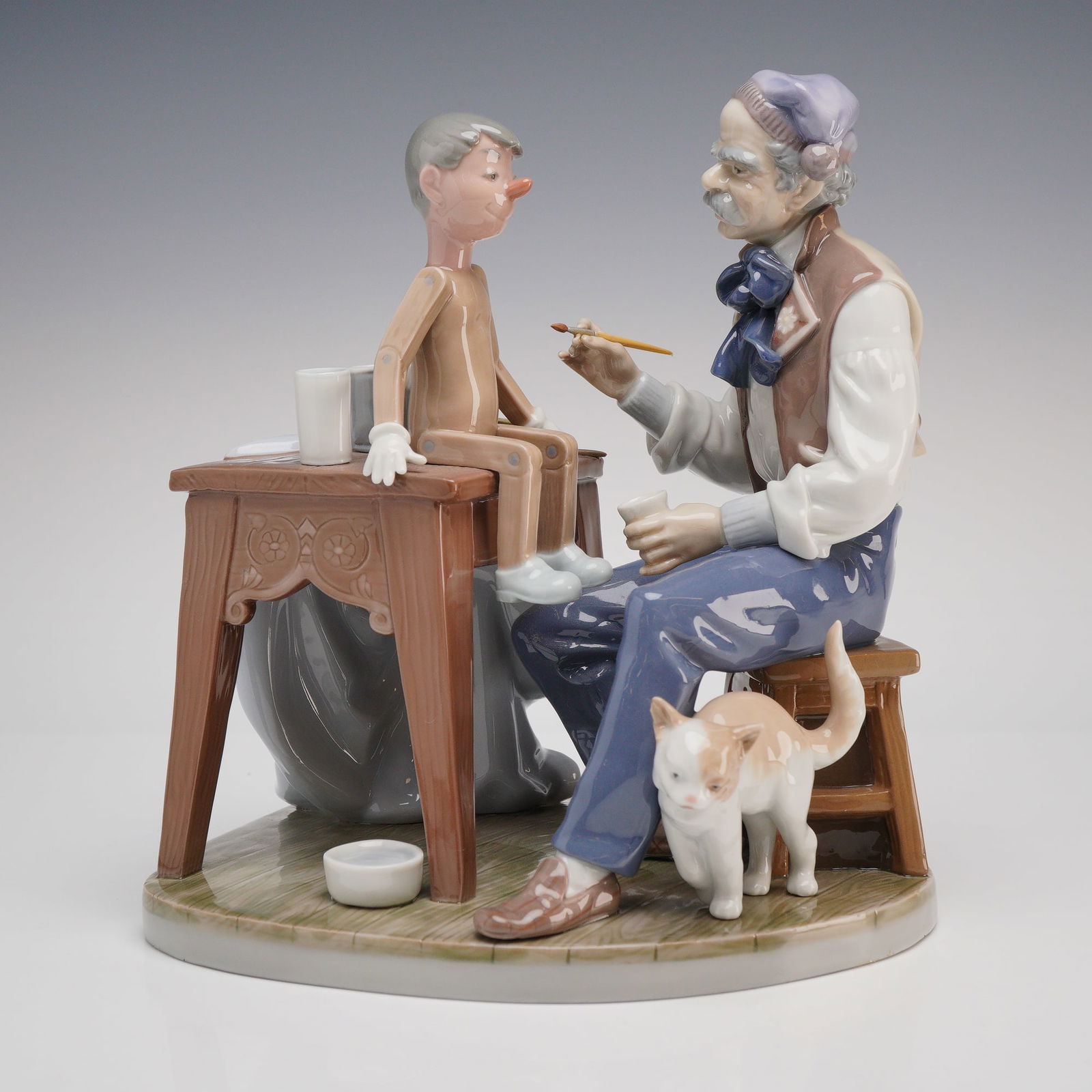 Lladro The Puppet Painter Porcelain Figurine, Model 5396: This is a highly detailed Lladro glazed porcelain figurine titled "The Puppet Painter," model number 5396. The piece depicts the classic scene of the woodcarver Geppetto finishing his creation,