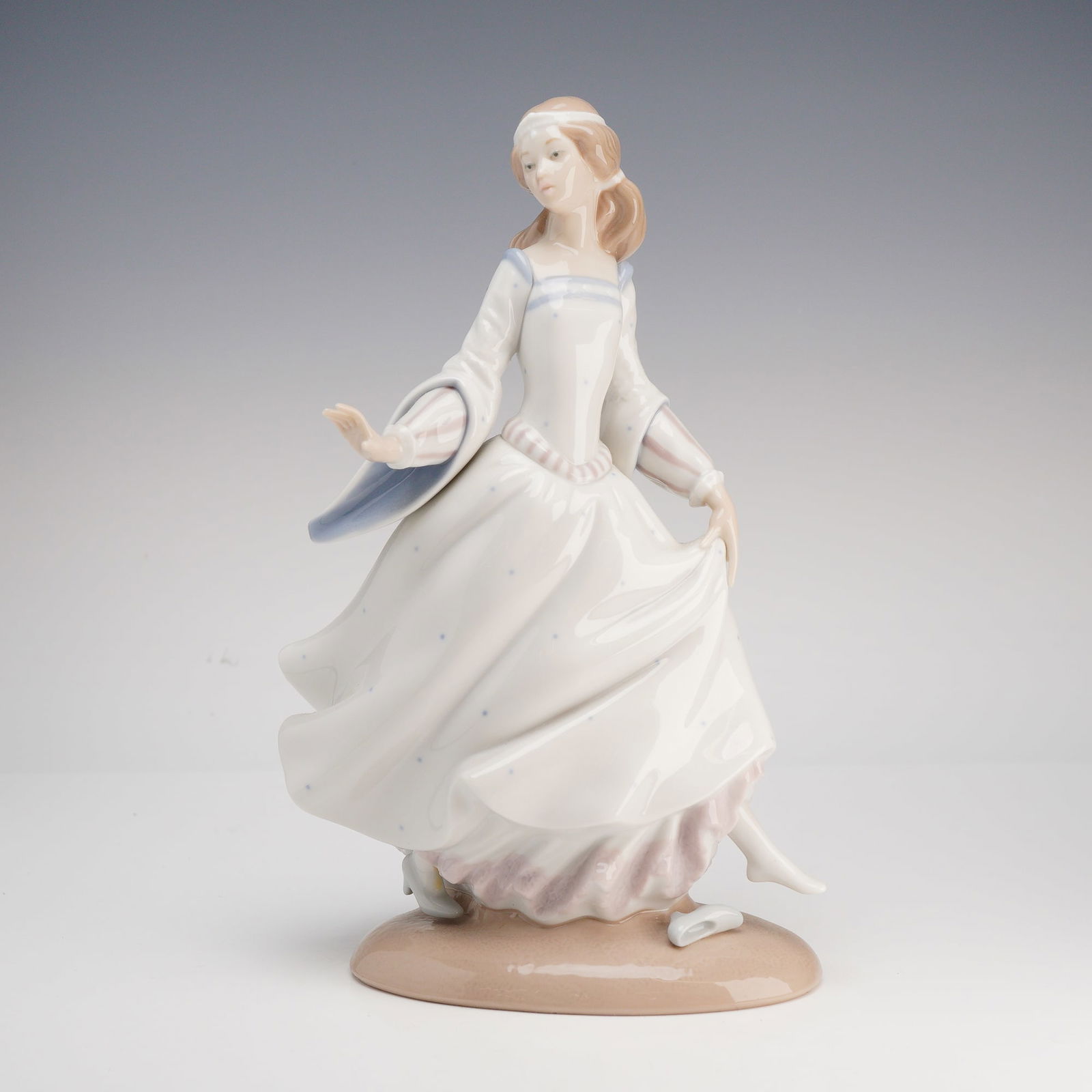 Lladro, Cinderella Figurine #4828: A fine glazed porcelain figurine by Lladro titled Cinderella (model #4828), designed by sculptor Alfredo Ruiz. The piece depicts the fairy tale character in a hurried, graceful pose as she flees the