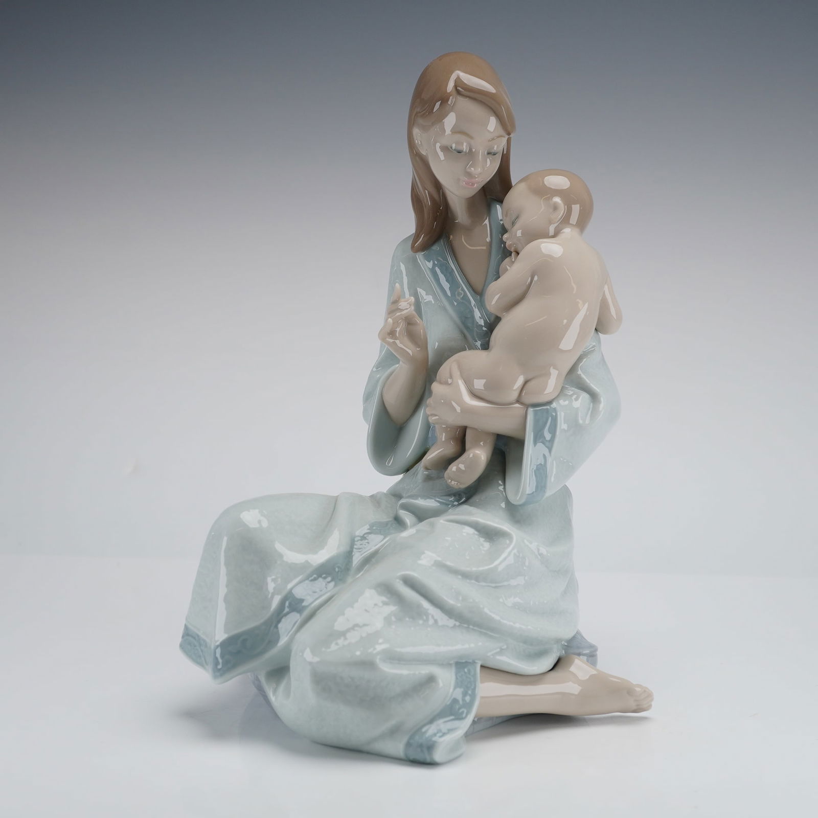 Lladro Hand-Painted Porcelain Figurine, Sleep My Love, Model 8030: A glossy hand-painted Lladro porcelain figurine, Sleep My Love (model 8030), that depicts a seated mother holding a sleeping infant. Marked LLADRO / HANDMADE IN SPAIN / VALENCIA and impressed 8030.