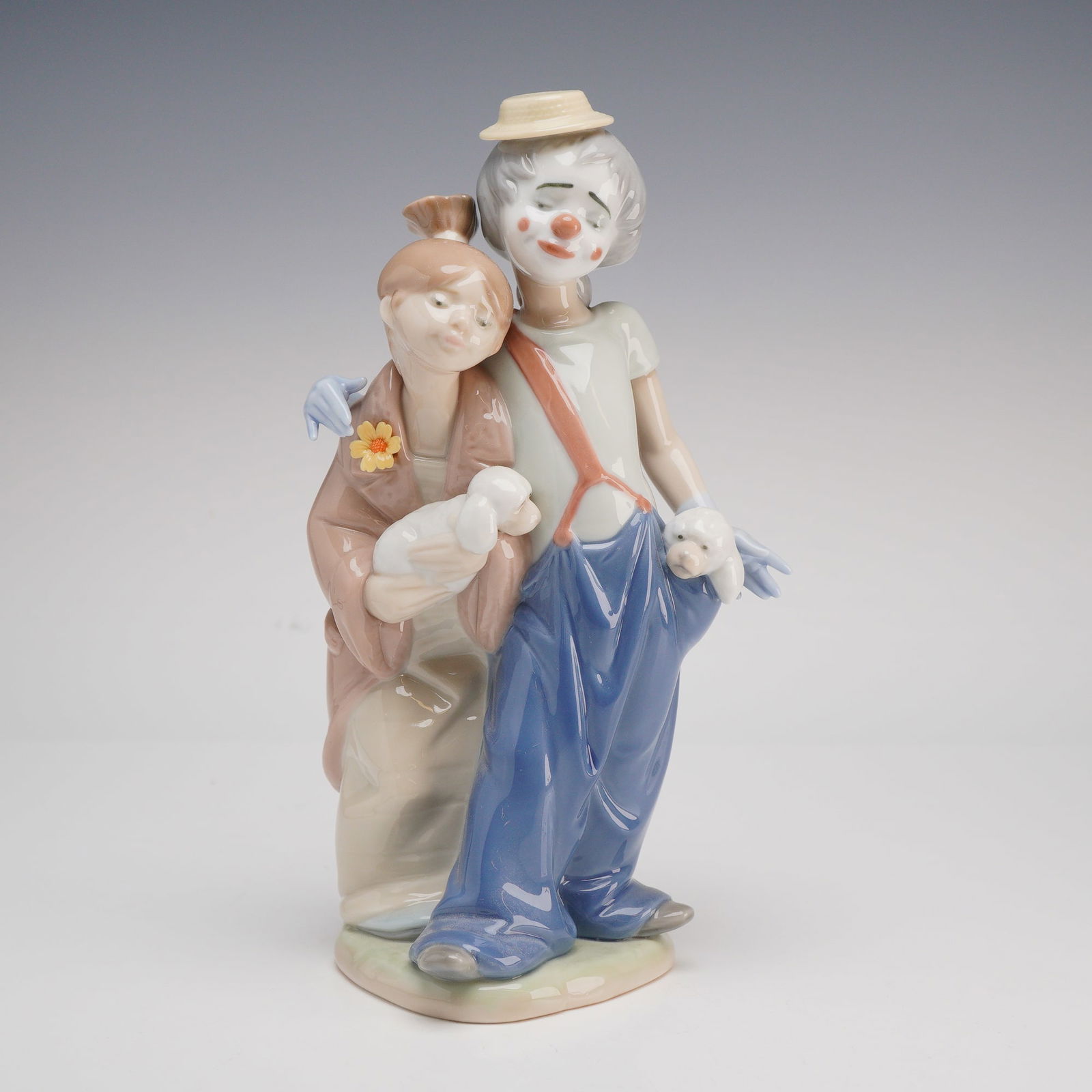 Lladro, Pals Forever #7686: A glazed porcelain figurine from Lladro titled "Pals Forever" (model #7686), depicting a charming pair of clowns in a gentle embrace. The male clown is dressed in oversized blue overalls with a single