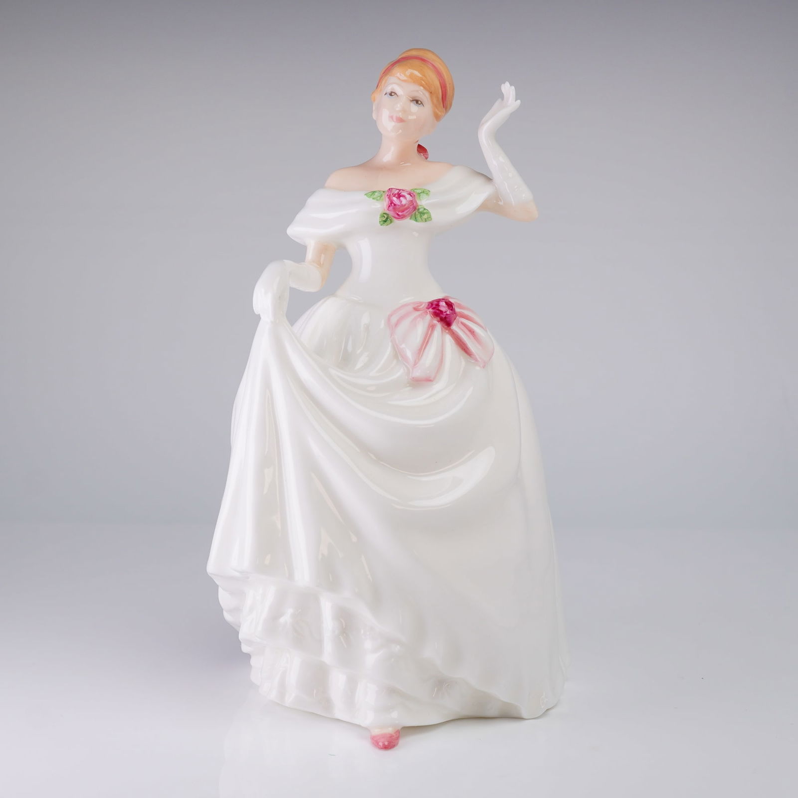 Royal Doulton Figurine Dawn HN3600: A glazed bone china figurine by Royal Doulton model HN 3600, titled "Dawn." The figure depicts a lady in a full-length, off-the-shoulder white ballgown. The figure has reddish-blonde upswept hair. The