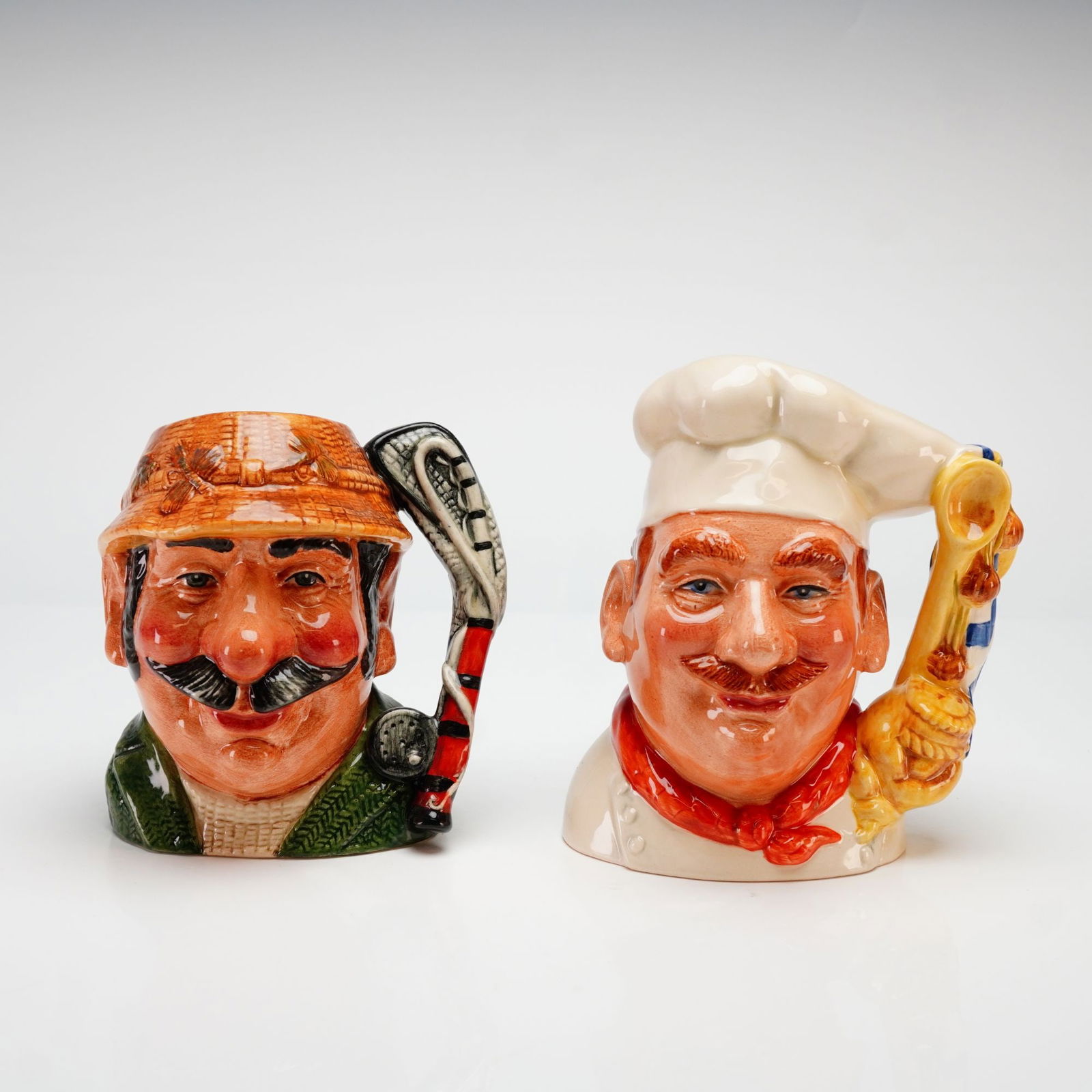 Royal Doulton The Chef and The Angler Character Jugs: A pair of hand-painted glazed earthenware character jugs produced by Royal Doulton, England. This set features The Chef (D7103) in the designated Odd Size (midsize) and The Angler (D7065) in the small