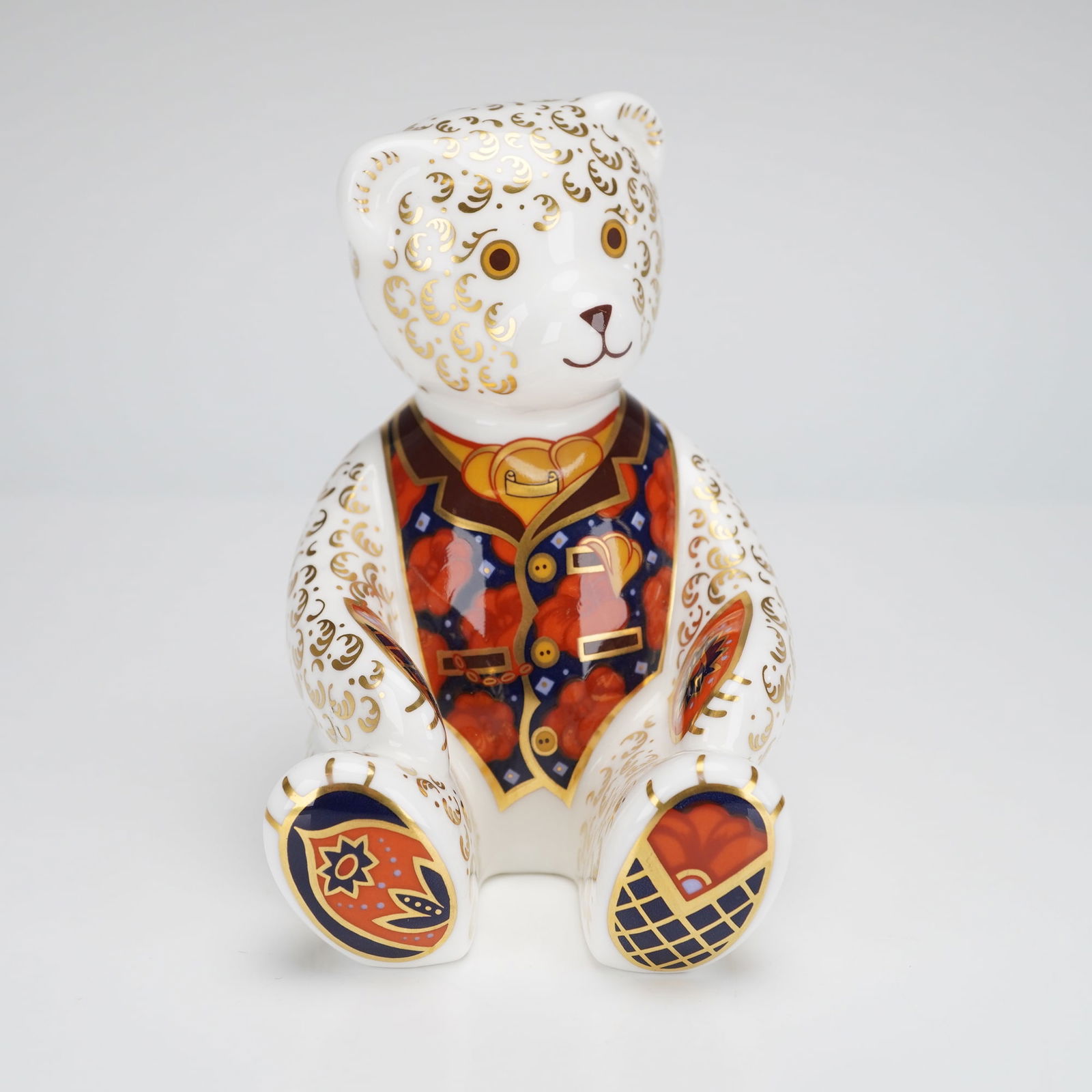Royal Crown Derby Gold Debonair Bear Collectors Guild Paperweight: A Royal Crown Derby figurine, modeled as a seated bear paperweight, dating to 1997. The piece is executed in English bone china and features a white ground heavily decorated with extensive gold
