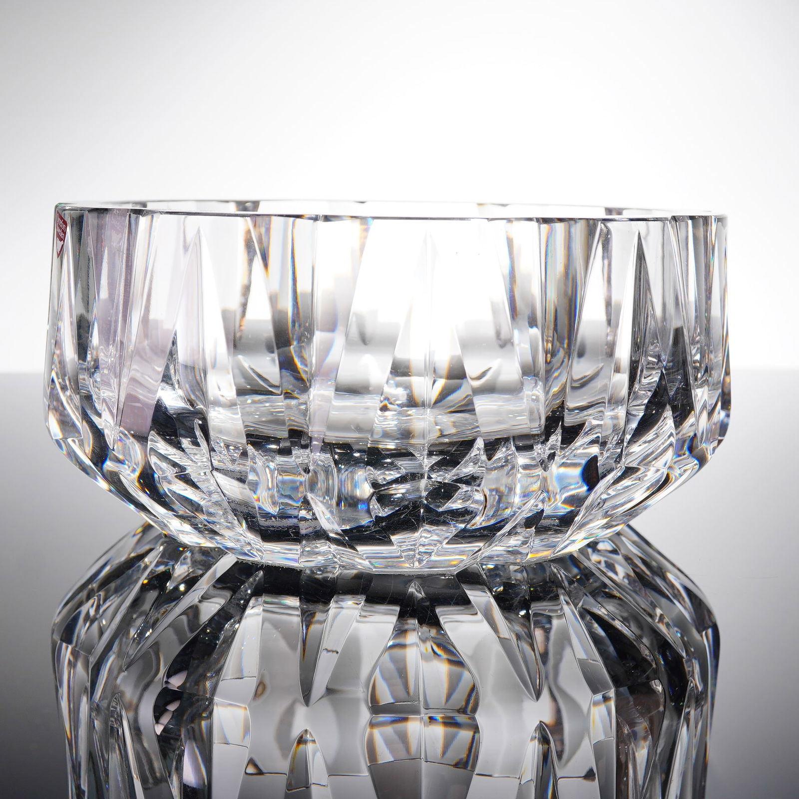 Orrefors Crystal Bowl: A single piece of heavy Swedish crystal glassware. The object is executed in a modernist style featuring sharp geometric faceting across its body, suggesting use as a bowl. The piece retains its origi
