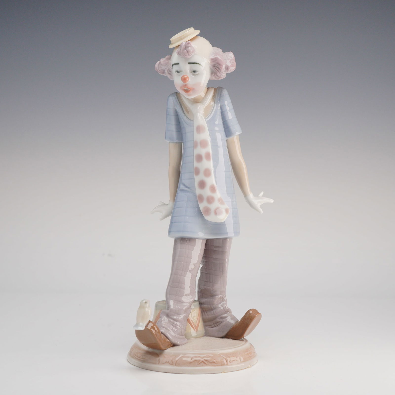 Lladro, Circus Days: This Lladro glazed porcelain figurine, titled Circus Days (model number 6916), depicts a whimsical clown in a classic performance pose. The figure features a standing clown with a melancholy expressio