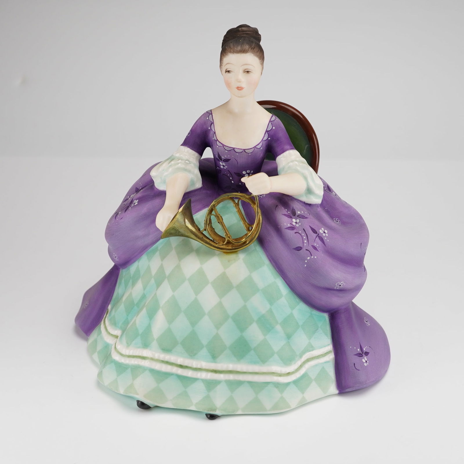 Royal Doulton Bone China Figurine French Horn HN2795: A Royal Doulton bone china figurine titled French Horn, model HN2795, from the Lady Musicians series. This piece was modeled by Peggy Davies and is dated 1975. The figurine depicts a seated woman in
