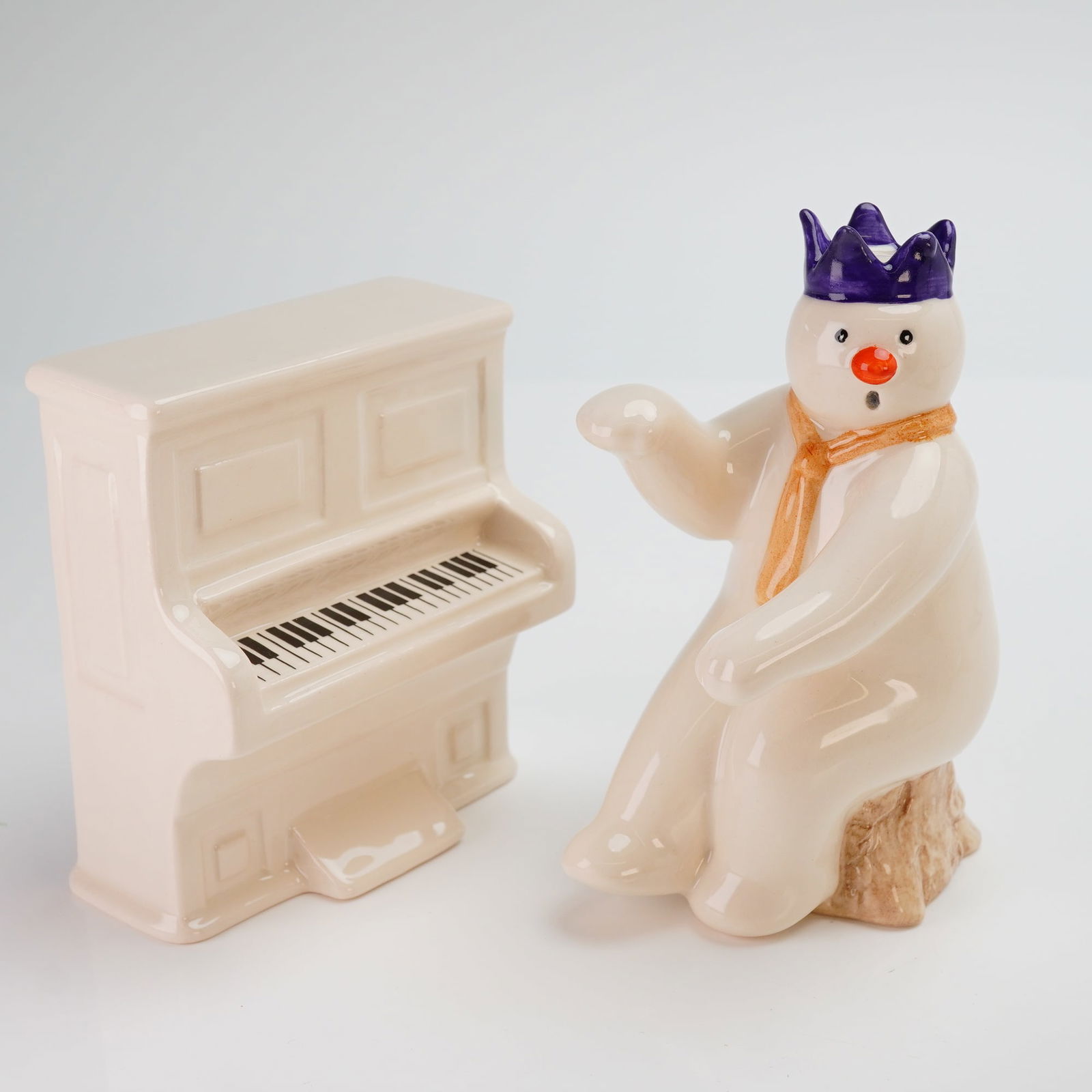 2pc Royal Doulton The Snowman Gift Collection Figurine with Piano: This 2pc Royal Doulton The Snowman Gift Collection consists of two glazed ceramic figurines: the Pianist Snowman (DS 12) and the Snowman's Piano (DS 13). The Pianist Snowman is modeled wearing a purpl