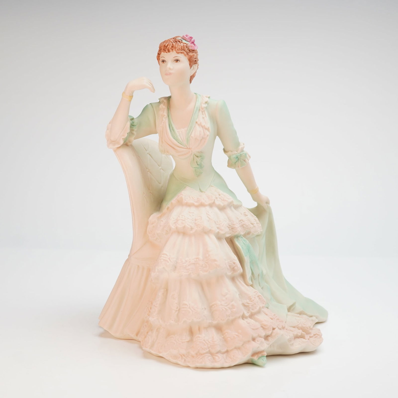 Coalport, Age of Elegance, Victoria Gardens Figurine: This Coalport figurine, titled Victoria Gardens from the Age of Elegance series, is a hand-decorated porcelain figure modeled by J. Bromley. The piece depicts a woman in late 19th-century attire seate