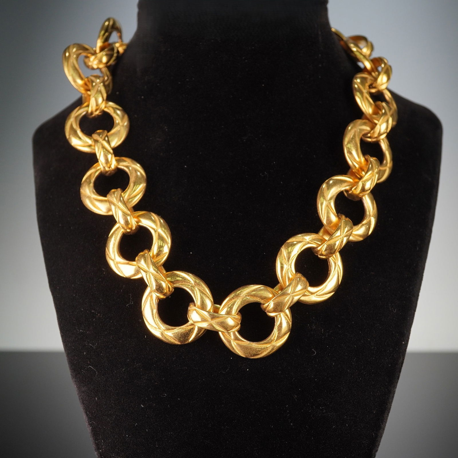 Chanel Gold-Tone Bold Link Necklace: A bold, gold-toned link necklace featuring a repeating pattern of large, smooth circular links connected by smaller, textured links adorned with a raised, cross-hatch or quilted pattern. The metal exh
