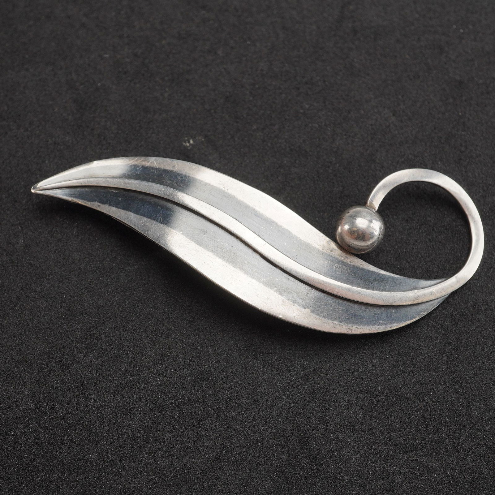 Delfino Taxco Sterling Silver Leaf Brooch Pin: A modernist sterling silver brooch pin by the Taxco maker Delfino. The design features a stylized, curving leaf form, accented with a polished silver sphere and a circular loop. The reverse is fitted