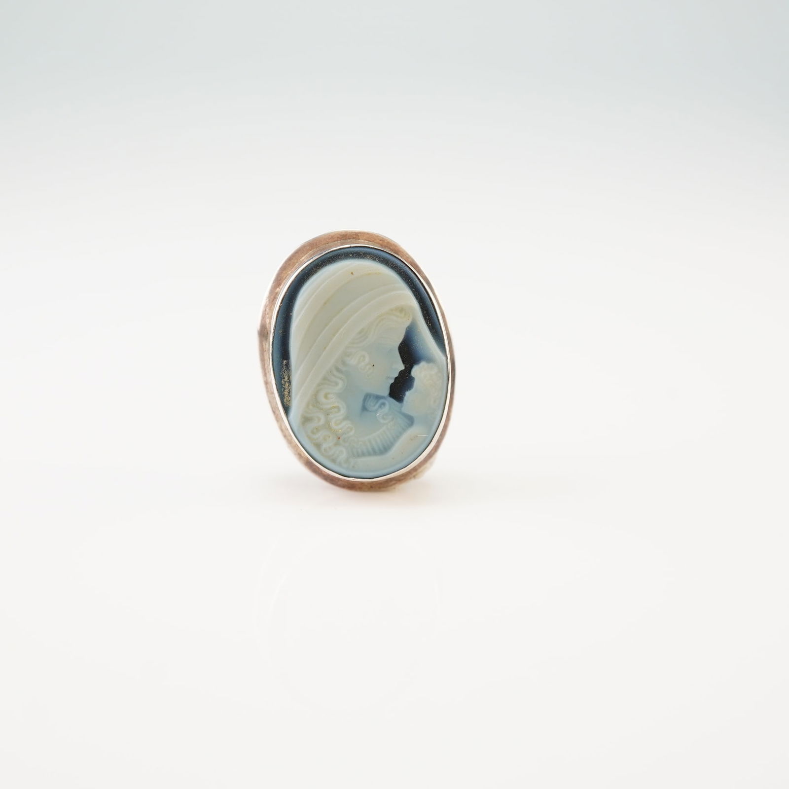 Italian Sterling Silver Mother and Child Blue Agate Cameo Brooch Pendant: This oval brooch-pendant is crafted in 925 sterling silver and features a bezel-set hardstone cameo. The blue agate cameo displays a finely carved white relief depicting a mother and child in a classi