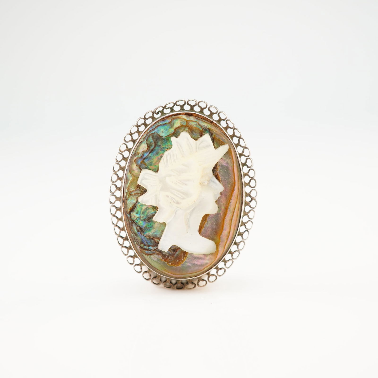 Mother of Pearl and Abalone Cameo Sterling Silver Brooch: This brooch is crafted in sterling silver and features a carved mother of pearl profile applied to an iridescent abalone shell background. The cameo is bezel-set within a decorative, scalloped openwor