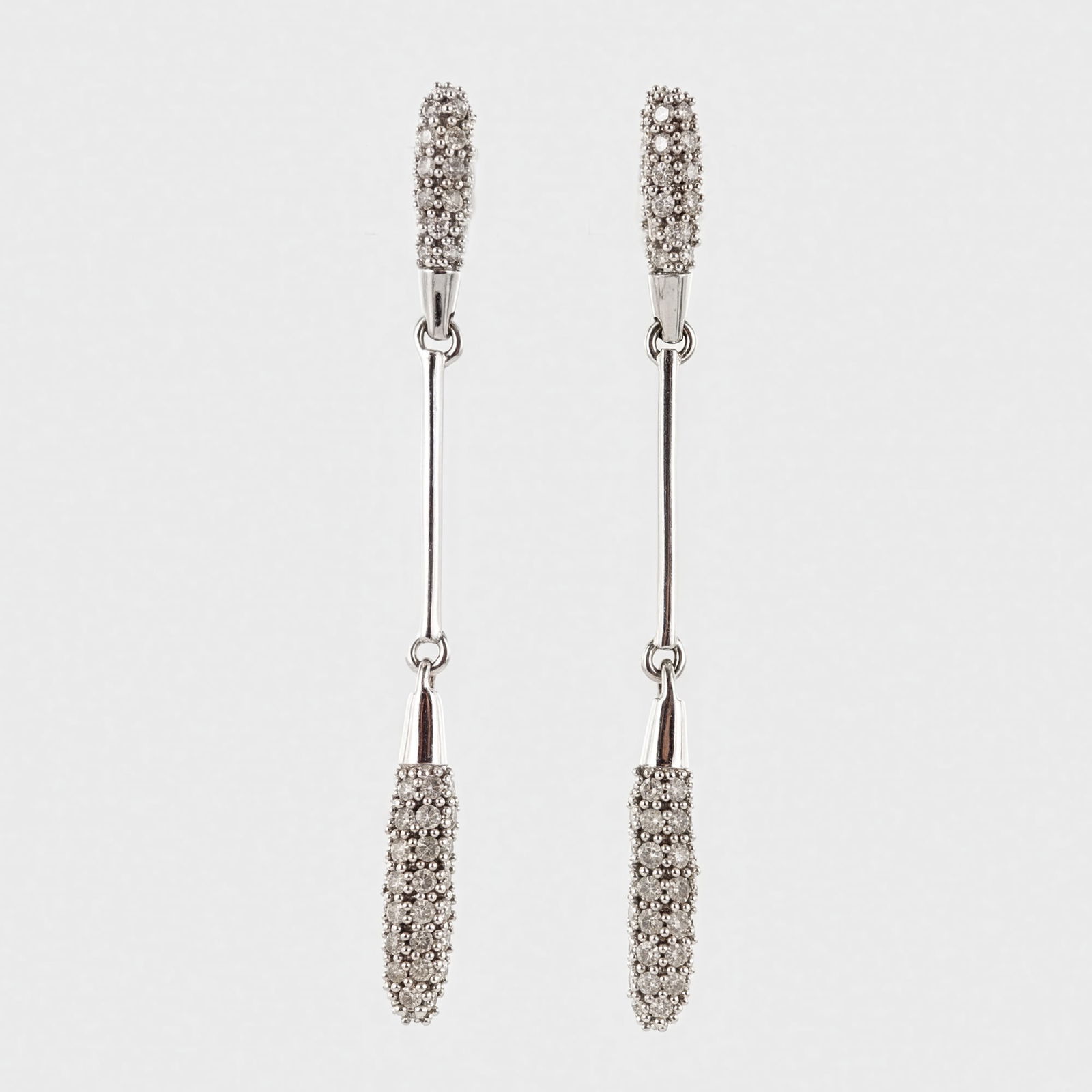 Pair of 10K White Gold and Diamond Drop Earrings: A pair of modern-style drop earrings, constructed of 10K white gold and adorned with diamonds. The design comprises a top curved element, pave-set with numerous small, round brilliant-cut diamonds, co