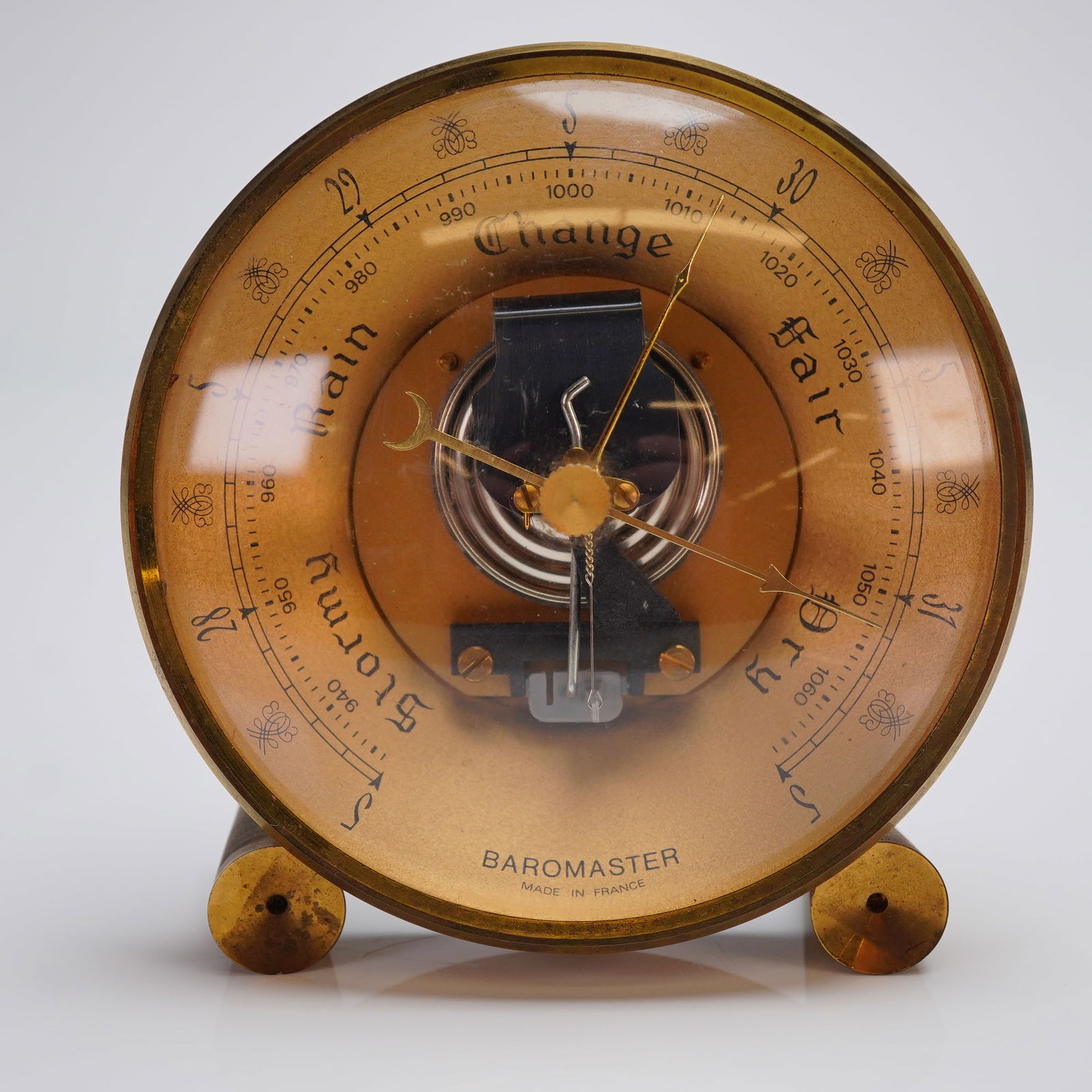 Baromaster French Desk Aneroid Barometer: A vintage desk-mounted aneroid barometer attributed to the Hoffritz retailer, marked Baromaster and Made in France. The instrument features a circular brass or lacquered metal casing supported by thre