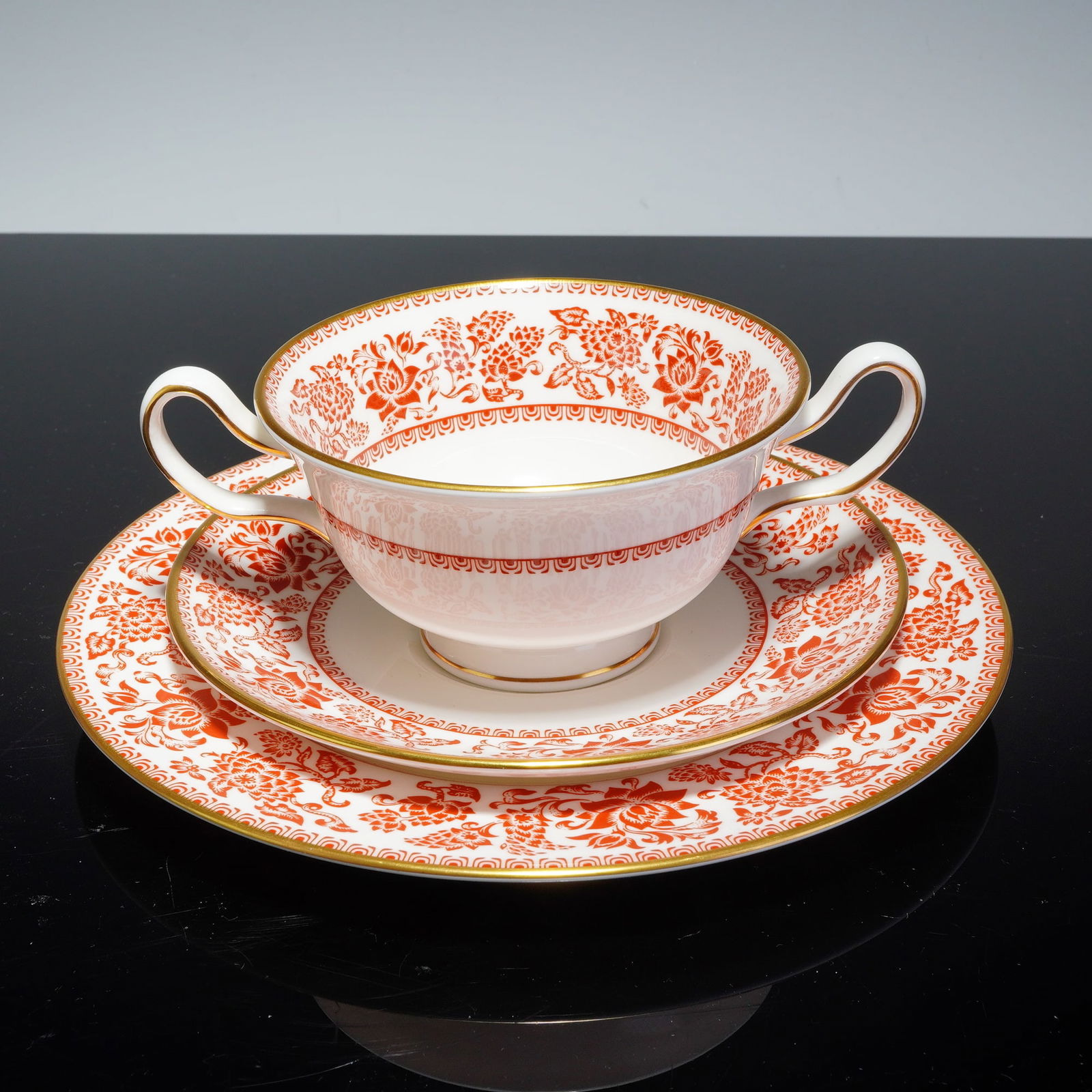 3pc Wedgwood Bone China Luncheon Set, Red Damask: The set comprises a twin-handled soup cup, a coordinating saucer, and a bread plate. Each piece is crafted from fine white bone china decorated with rust-red transfer-printed floral scrolls and foliat