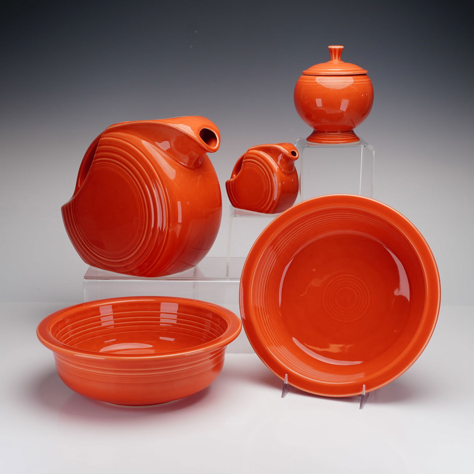 5pc Homer Laughlin Red Fiesta Tableware: A group of glazed ceramic tableware in the Red Fiesta pattern by Homer Laughlin. The collection consists of various serving and kitchen pieces including a large disk water pitcher, a small creamer, a