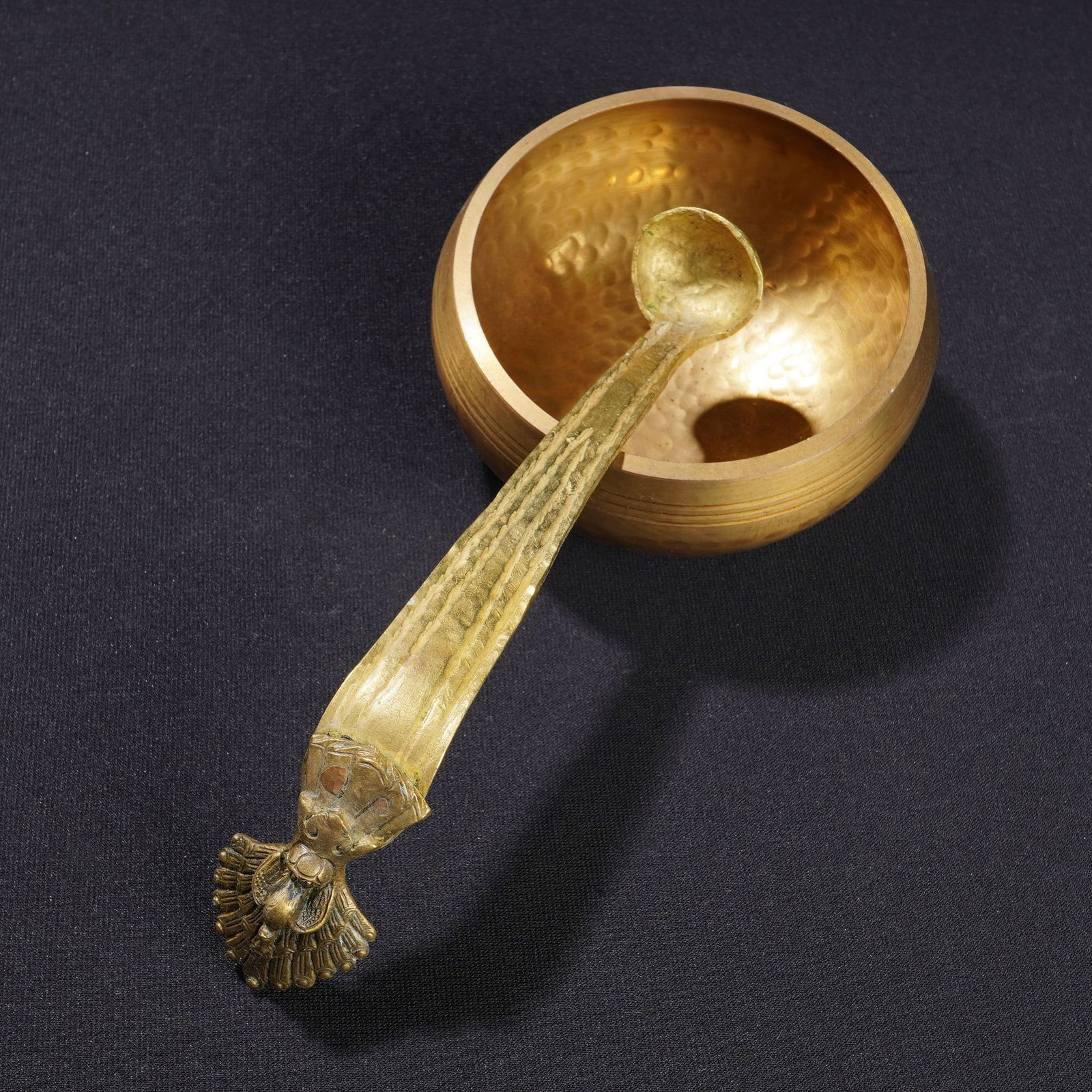 2pc Gold Tone Metal Bowl and Ornate Peacock Ladle: This two piece lot consists of a gold-tone metal bowl and a coordinating ornate ladle. The bowl is constructed from a yellow-toned metal alloy featuring a hand-hammered texture on the exterior