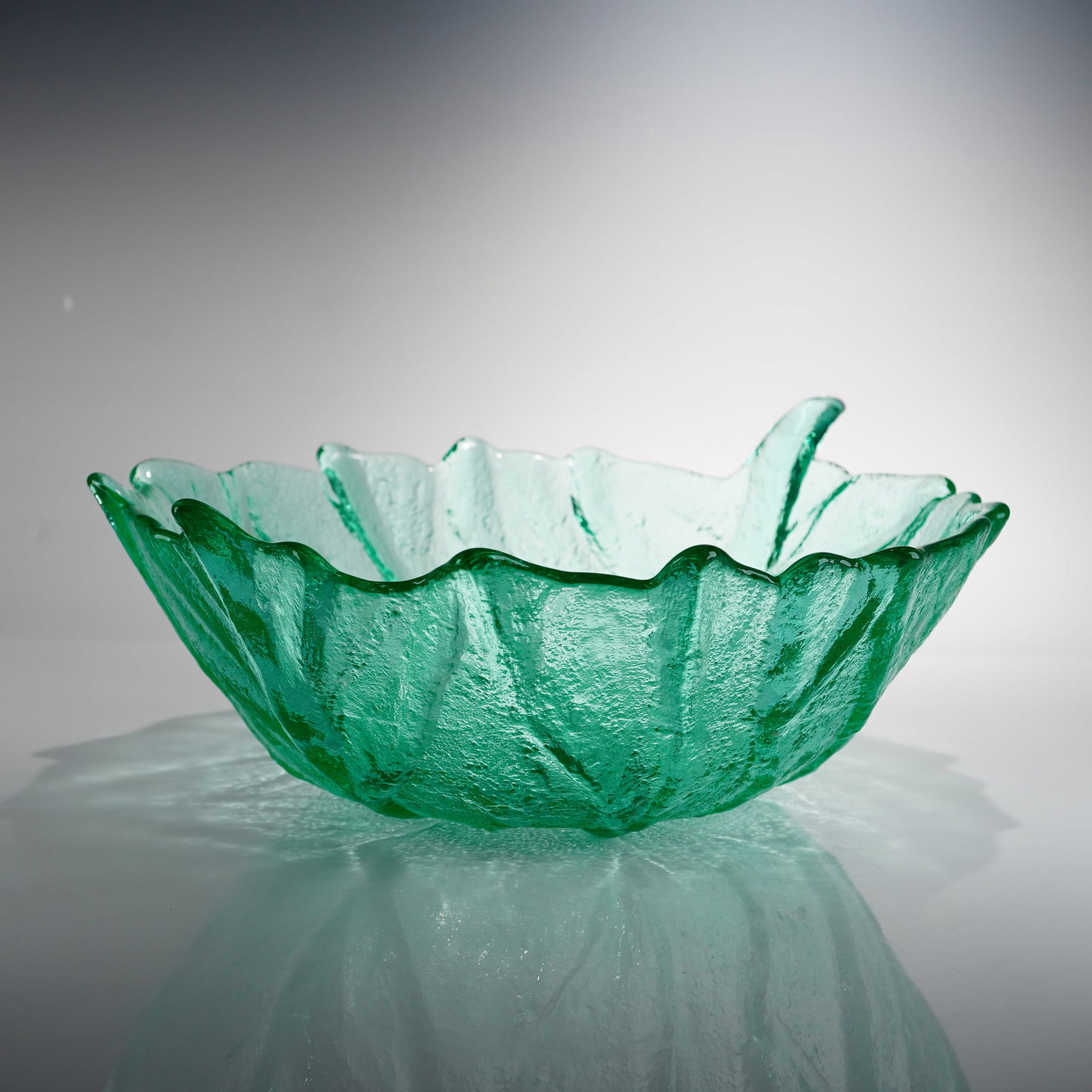 Blenko Handmade Textured Glass Leaf Shaped Serving Bowl: A large Blenko handmade green glass leaf shaped serving bowl, often referred to as the cabbage leaf pattern. This studio art glass piece is rendered in a vibrant emerald green color. The bowl is produ