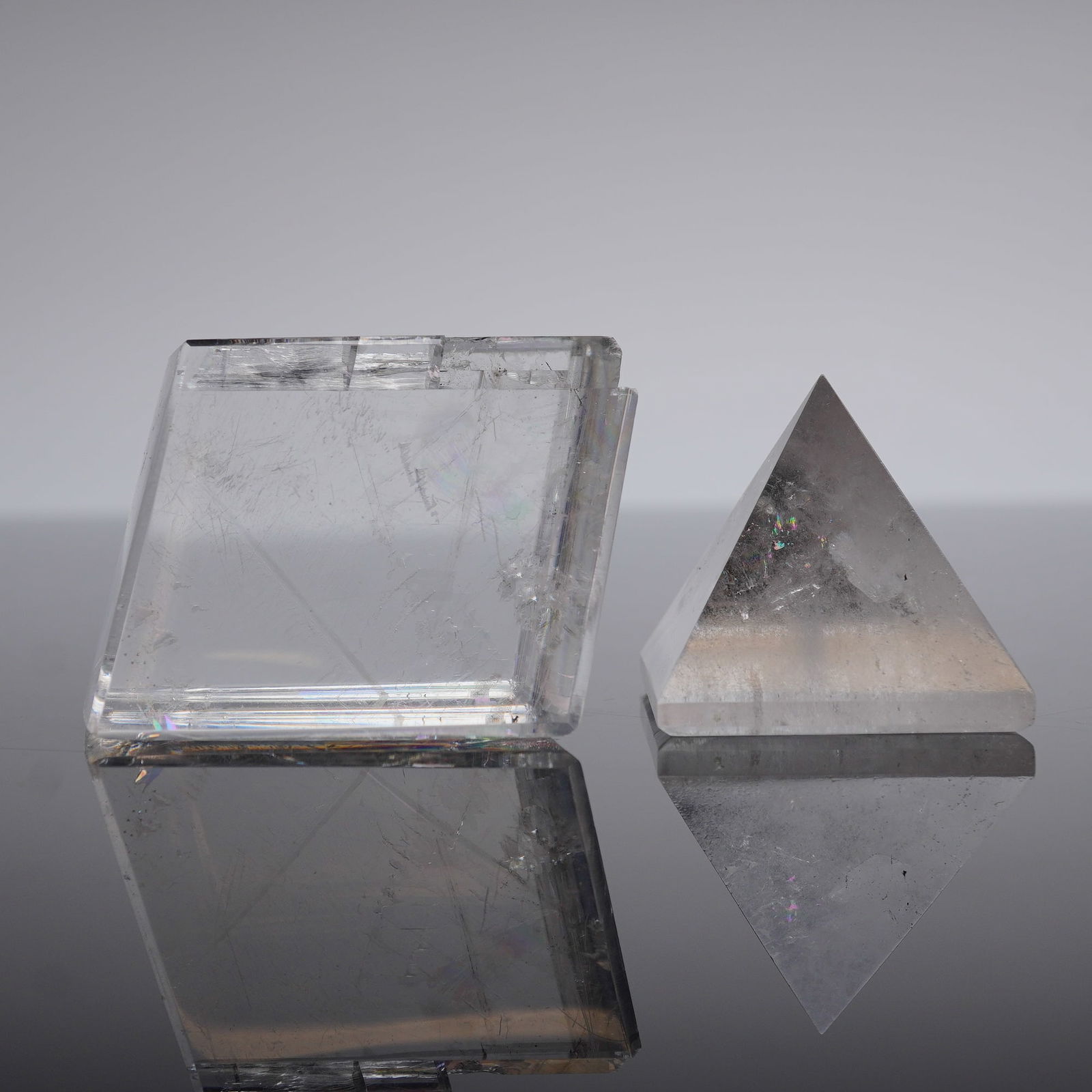 2pc Opal Calcite Prism and Quartz Pyramid Paperweights: A pair of polished mineral specimens, comprising one rectangular prism and one square-based pyramid. The prism specimen is likely optical calcite, referenced as 'Opal Calcite,' exhibiting highly trans