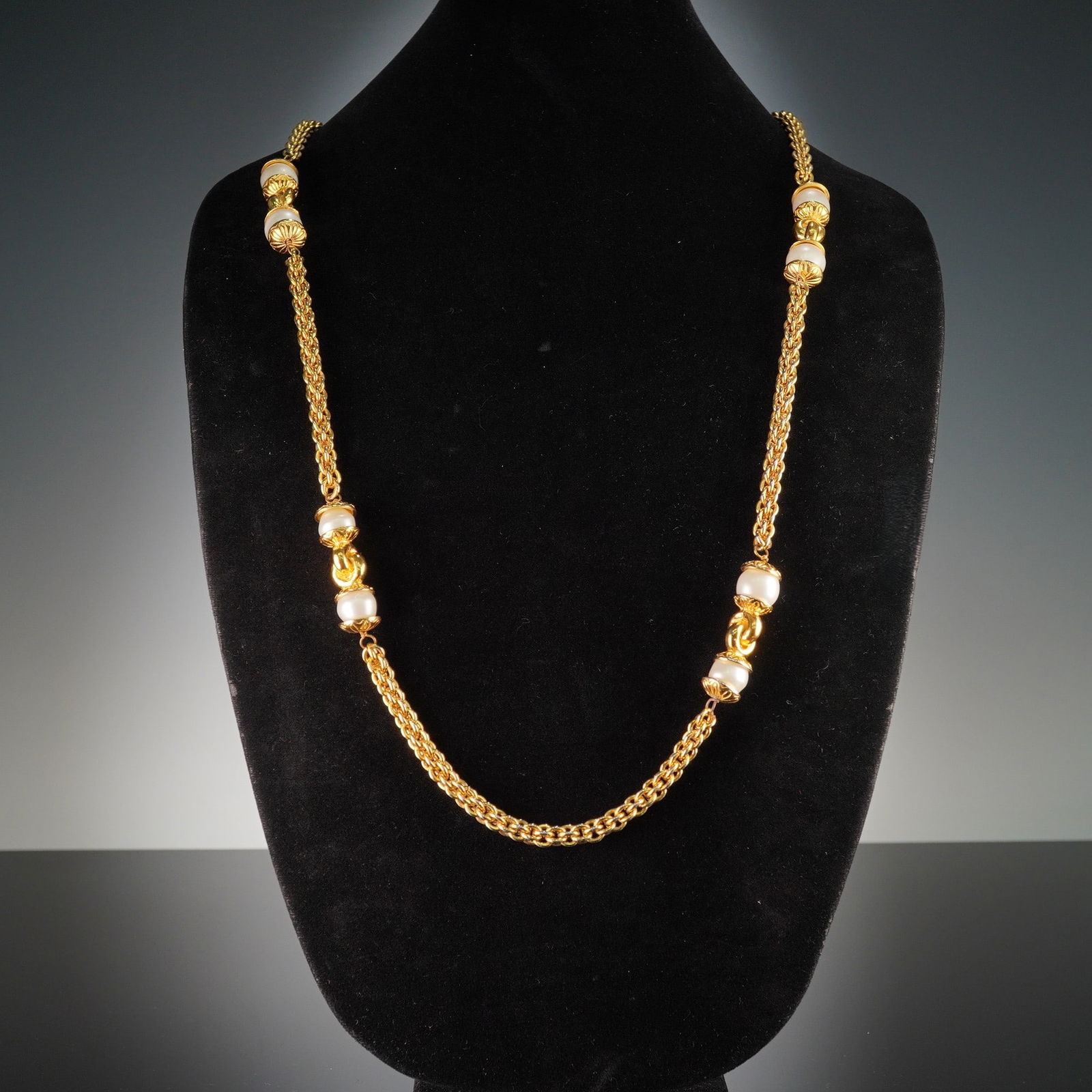 Chanel 1970s Gold Plated Faux Pearl Sautoir Necklace: A Chanel 1970s gold plated faux pearl sautoir necklace. This long necklace is constructed from a double-strand, golden-colored metal chain. Periodically spaced along its length are sections featuring