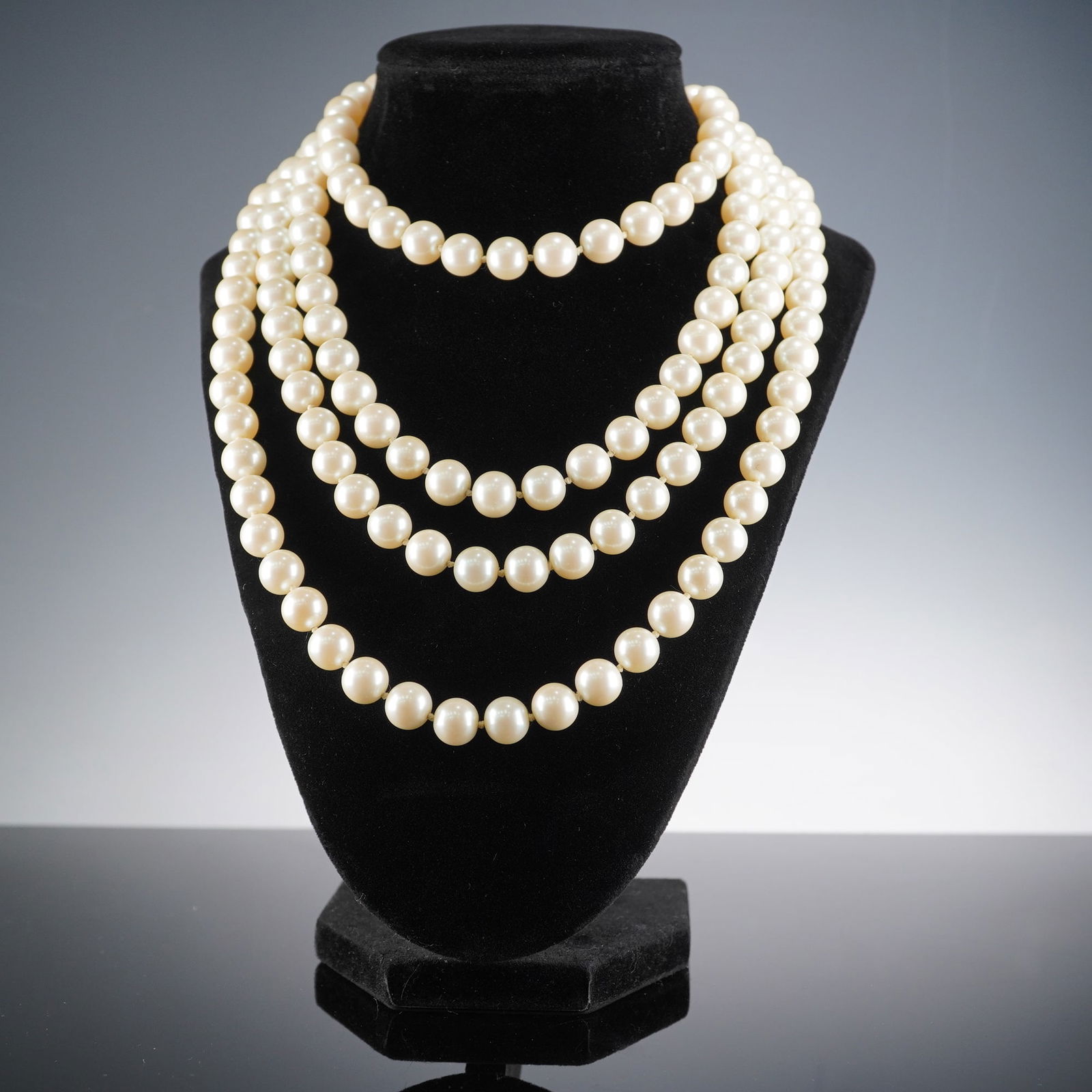 Very Long Continuous Strand Simulated Pearl Necklace: A very long continuous strand necklace featuring individually knotted spherical beads resembling high-quality cultured pearls, exhibiting a creamy-white color and high luster. The single strand constr
