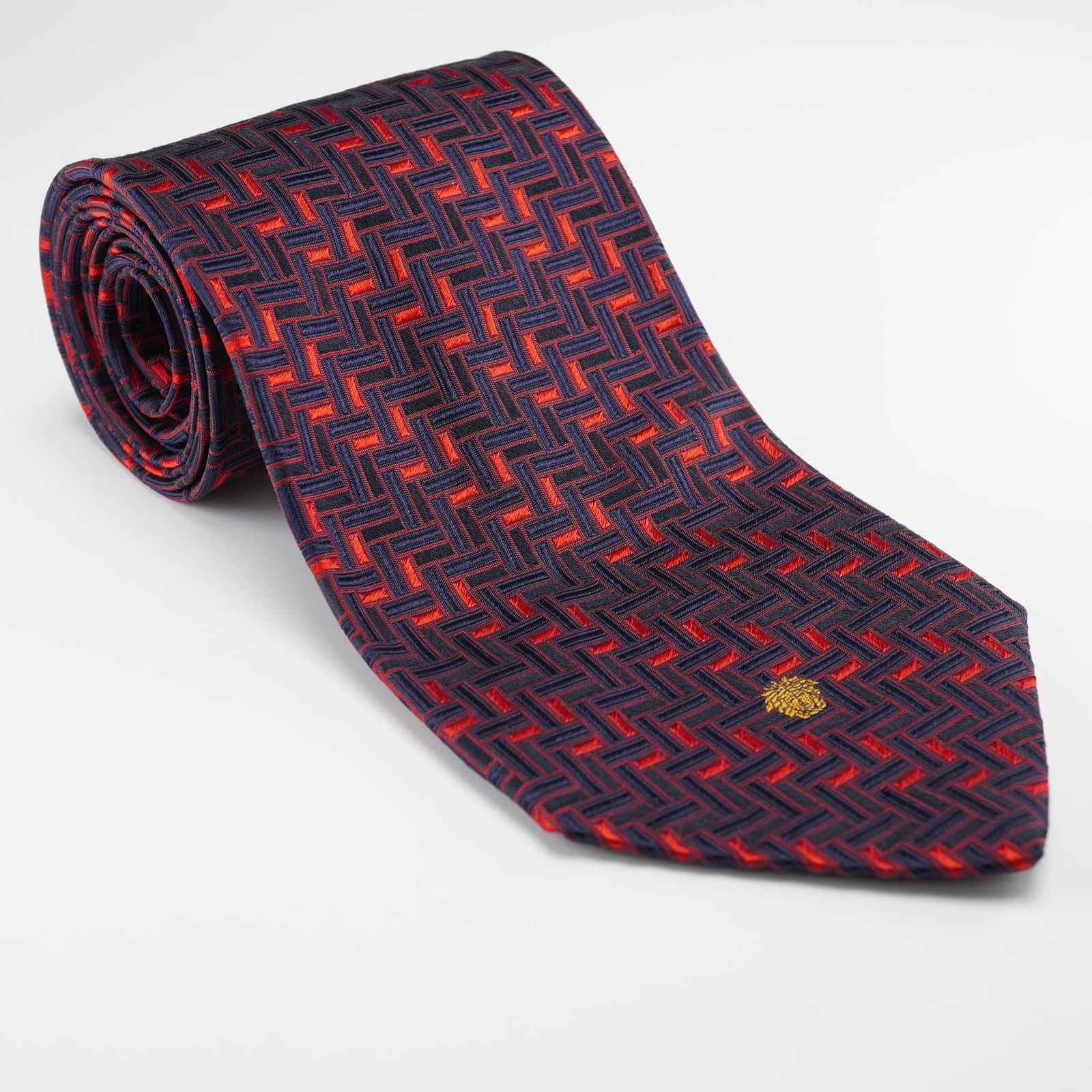 Versace Mens 100% Silk Geometric Tie: A Versace Mens 100% Silk Geometric Tie. This modern mens necktie is crafted from 100% silk, as indicated by its care label. It features a repeating geometric pattern of interlocking navy blue and brig