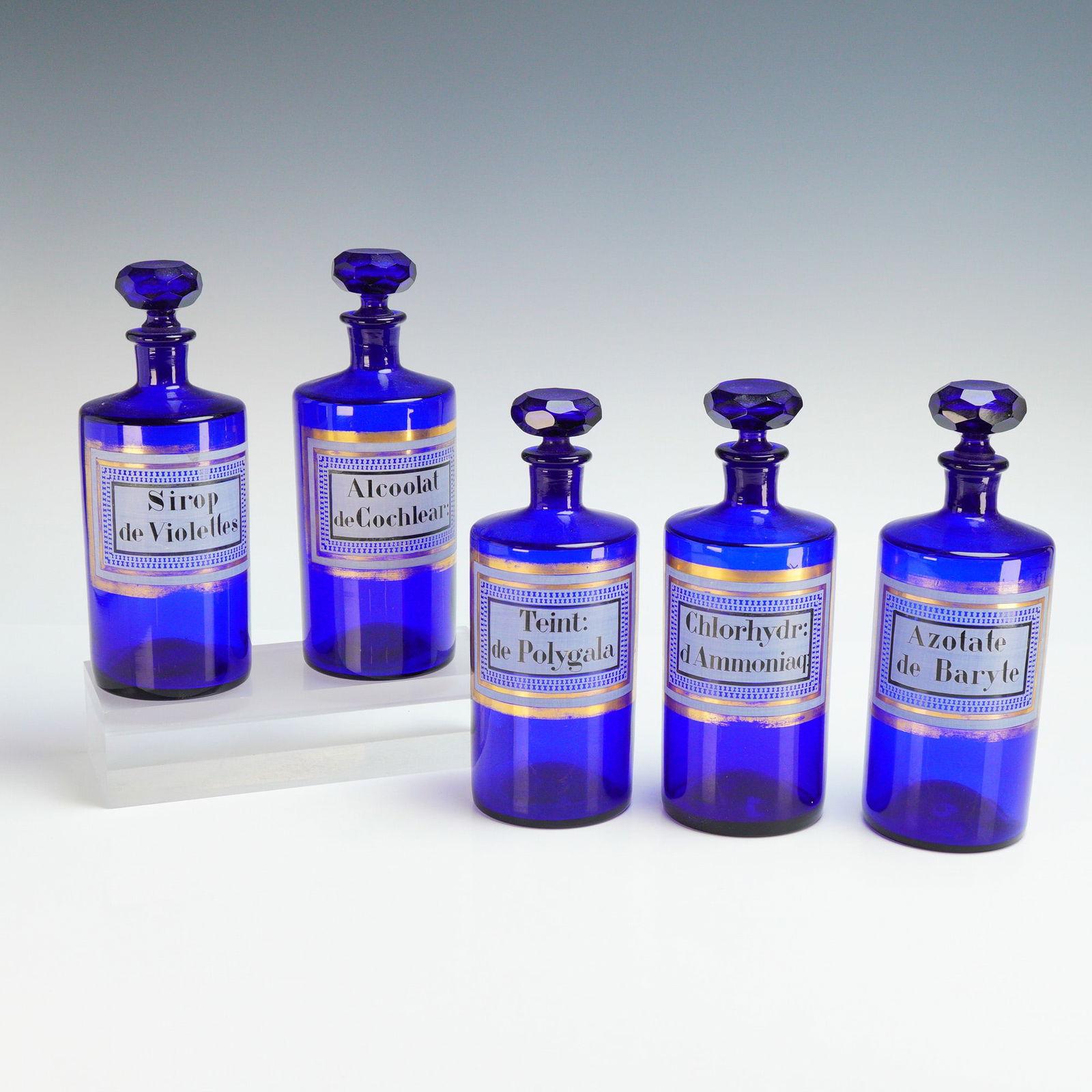 5pc French Cobalt Blue Glass Apothecary Bottles: A set of 5 antique French cobalt blue glass apothecary bottles dating to the late 19th century. Each cylindrical vessel is constructed from deep cobalt blue glass and features a matching faceted glass