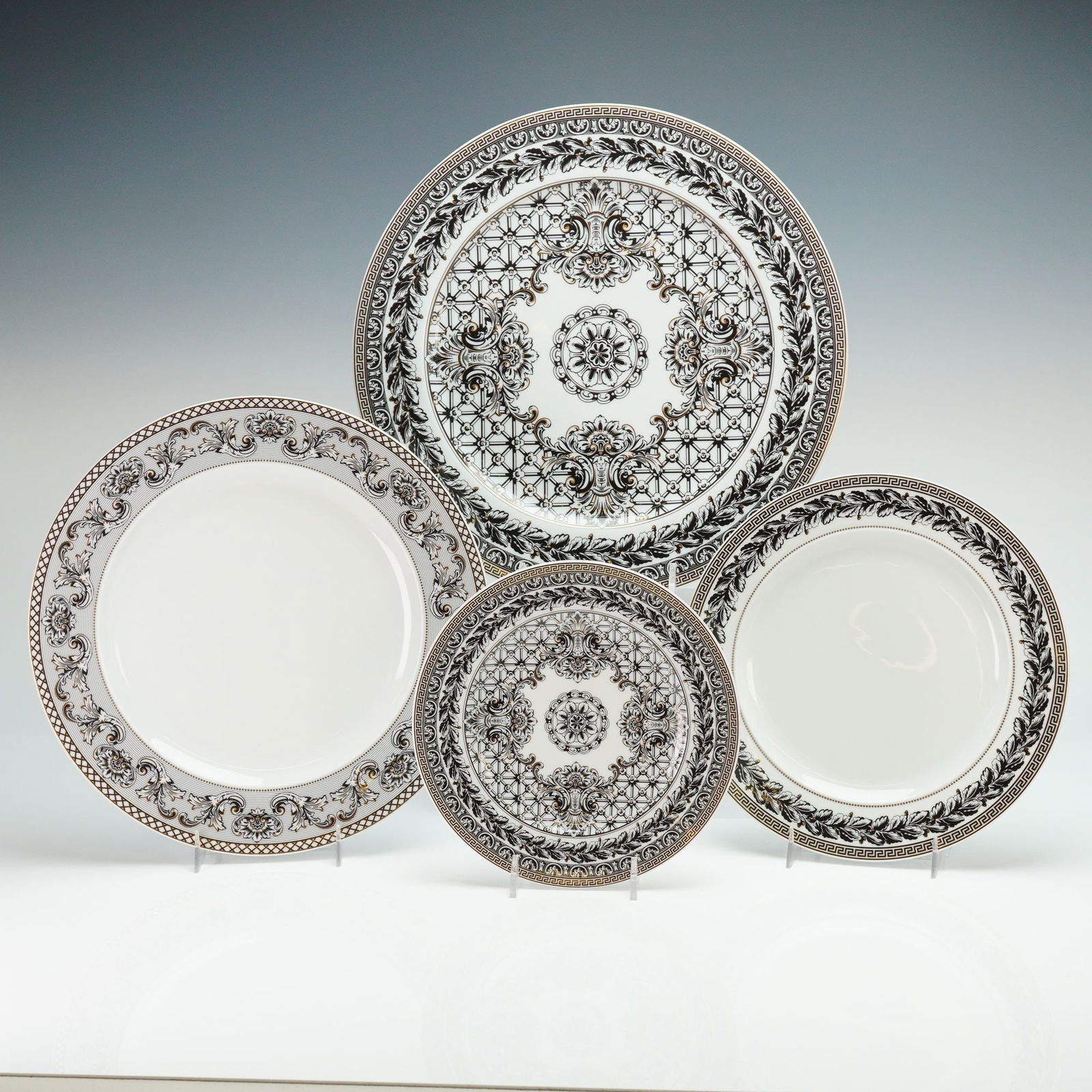 4pc Versace Rosenthal Porcelain Plate Set, Marqueterie: Porcelain plate set manufactured by Rosenthal for Versace in the Marqueterie pattern. The collection features a Neoclassical design palette of black, white, and gold tones. The decoration consists of