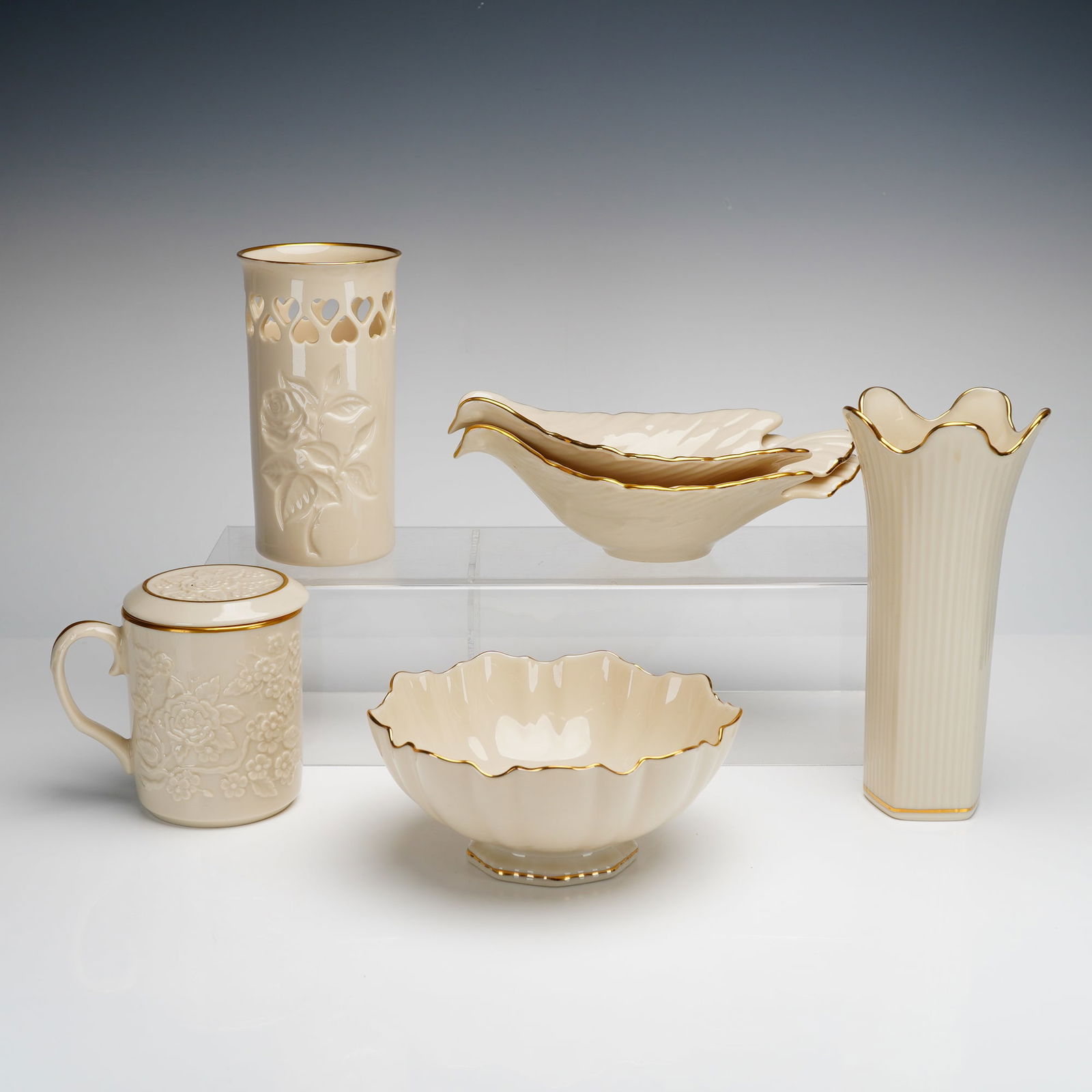 6pc Lenox Bone China Tableware and Decorative Items: A collection of Lenox porcelain items featuring hand-decorated 24k gold trim. The assortment includes a cylindrical vase with a reticulated heart-motif collar and embossed rose design, a lidded mug wi