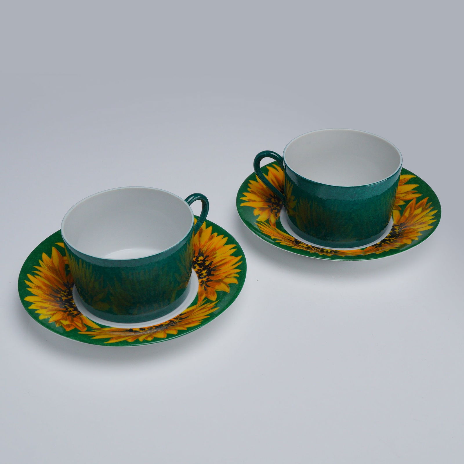 4pc Laure Japy, Made in Limoges for Barney's New York, Teacups & Saucers: Features two sets of Laure Japy teacups with matching saucers, decorated in a vibrant sunflower motif against a Tournesol green background on the saucers. The cups are finished in a Tournesol green.