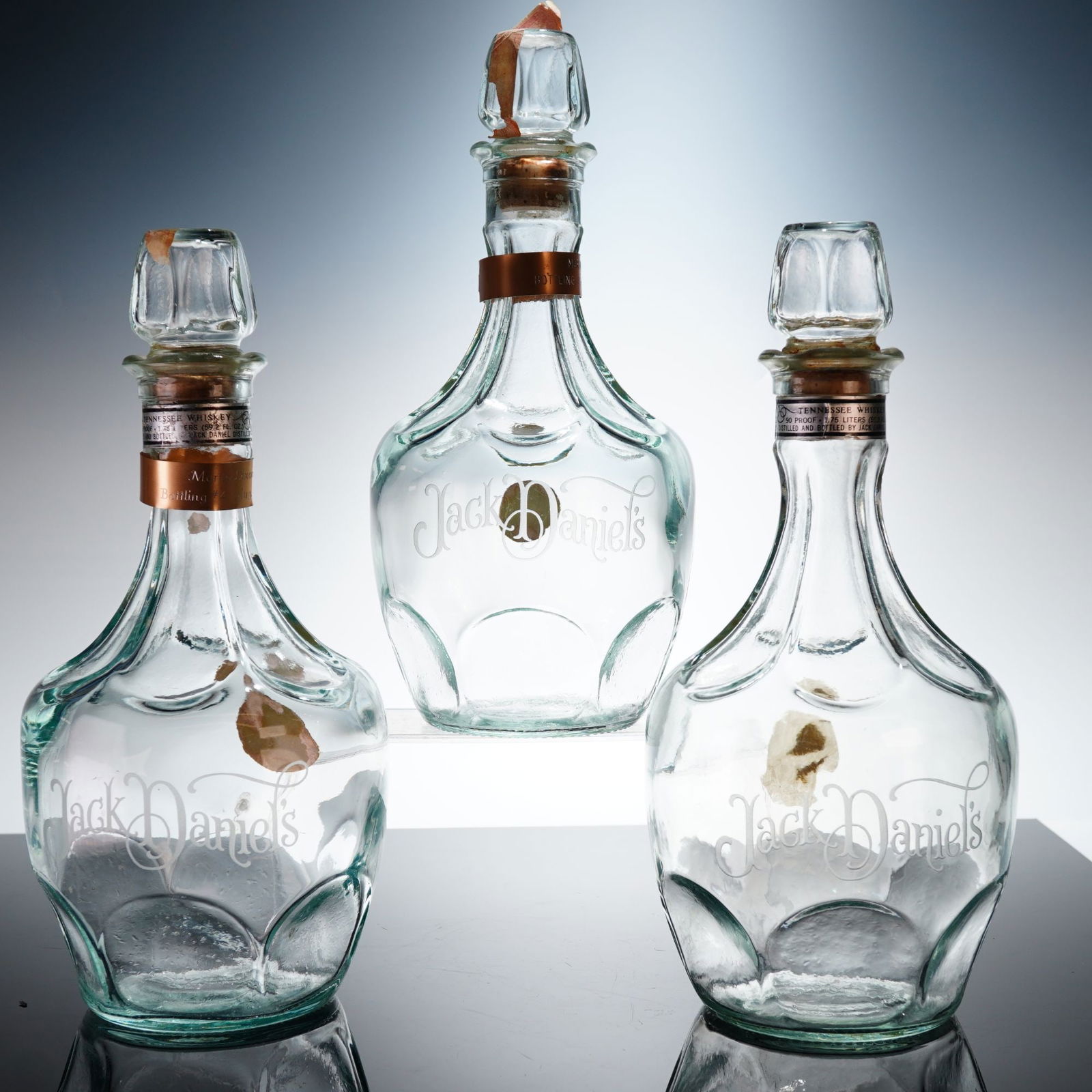 3pc Jack Daniels Decanters with Martin Dixon Bottling Bands: Three Jack Daniel's Belle of Lincoln clear glass whiskey decanters. Each vessel features a bulbous body with a faceted base and a tapered neck. The front of each decanter is adorned with etched Jack D