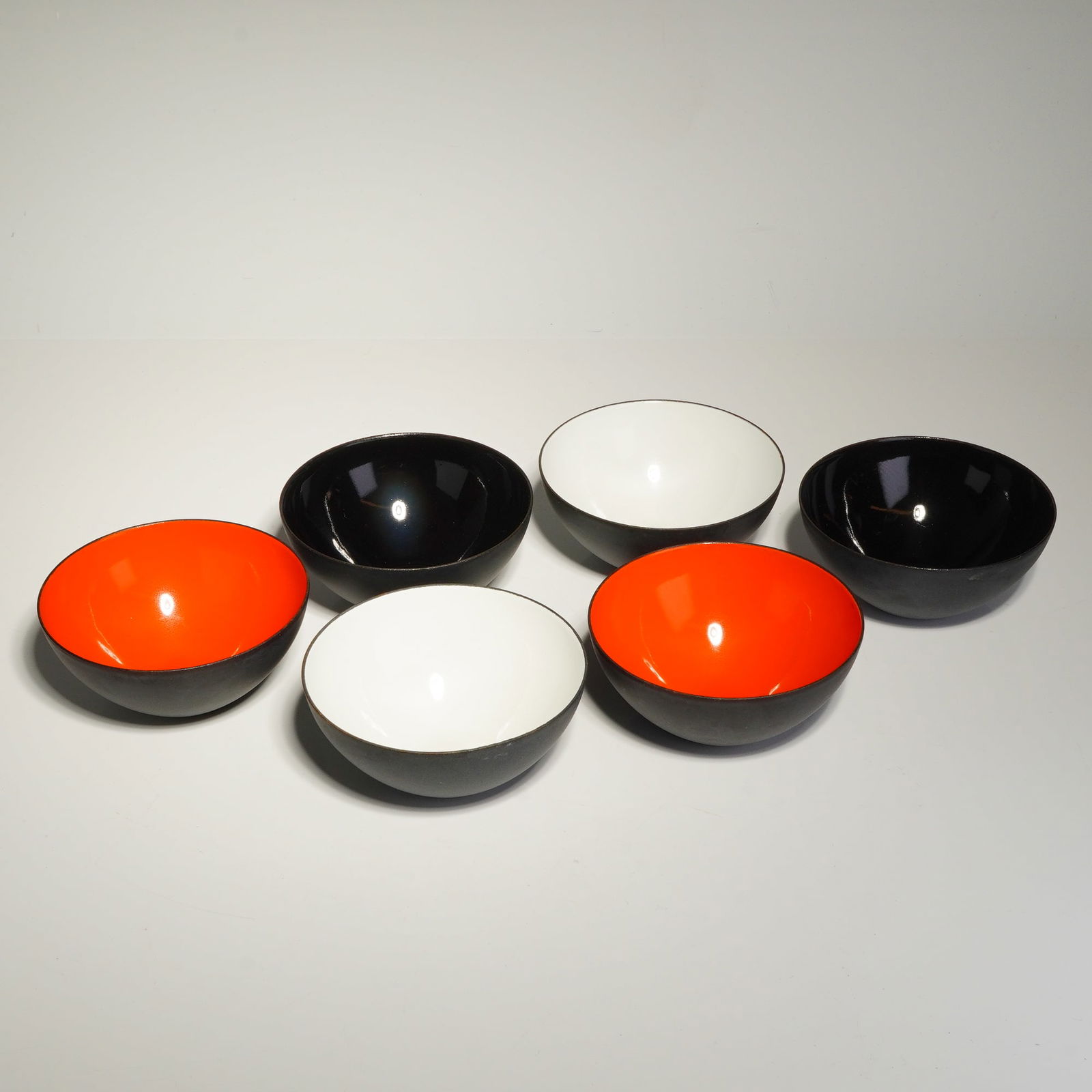 6pc Mid-Century Modern Krenit Enameled Steel Bowls: A collection of six small Krenit bowls constructed of thin-walled steel, showcasing a minimalist, hemispherical form. The bowls feature a matte black sandblasted enamel exterior, providing a textured
