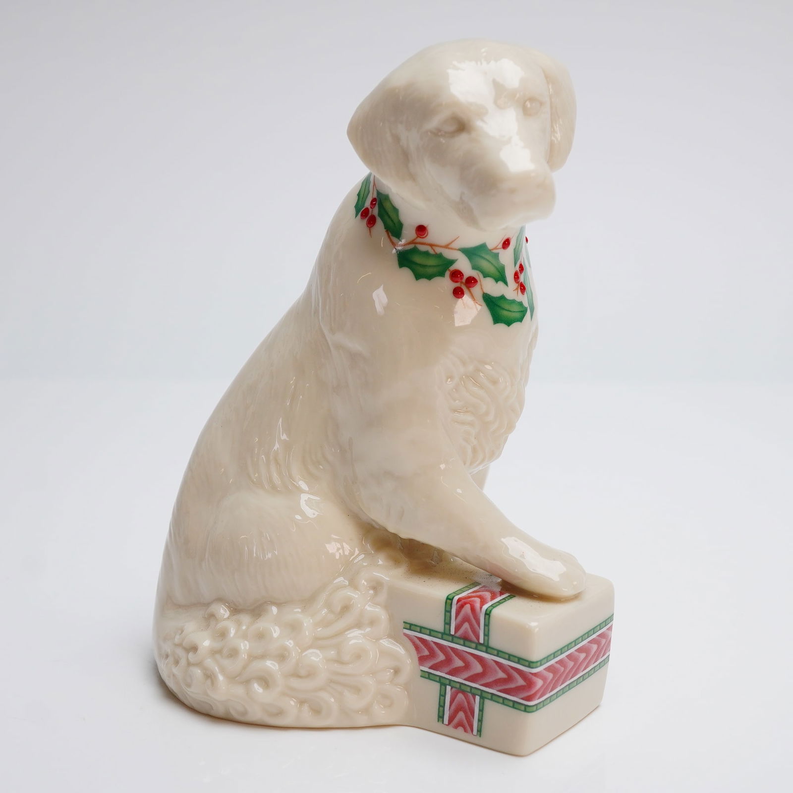 Lenox Porcelain 1992 Annual Holiday Retriever Figurine: The piece is executed in glazed porcelain with an ivory-color finish, depicting a seated Labrador or Retriever dog styled as a Christmas accessory. The dog wears a painted collar featuring green holly