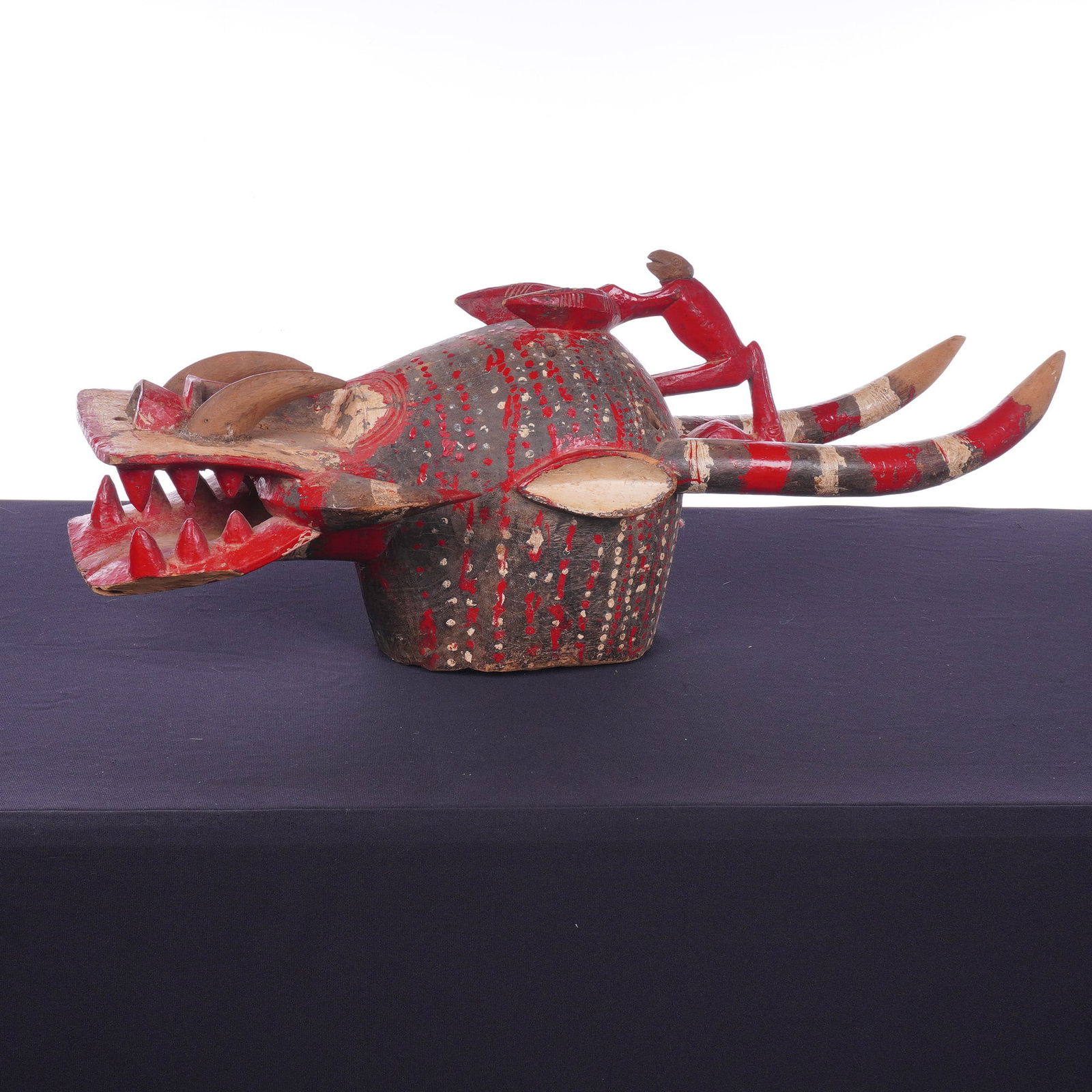 African Senufo Firespitter Ceremonial Mask: A Senufo Firespitter ceremonial mask, also known as a Kponyungo. This large polychrome helmet mask is hand-carved from wood and features two prominent vertically rising horns decorated with red and wh