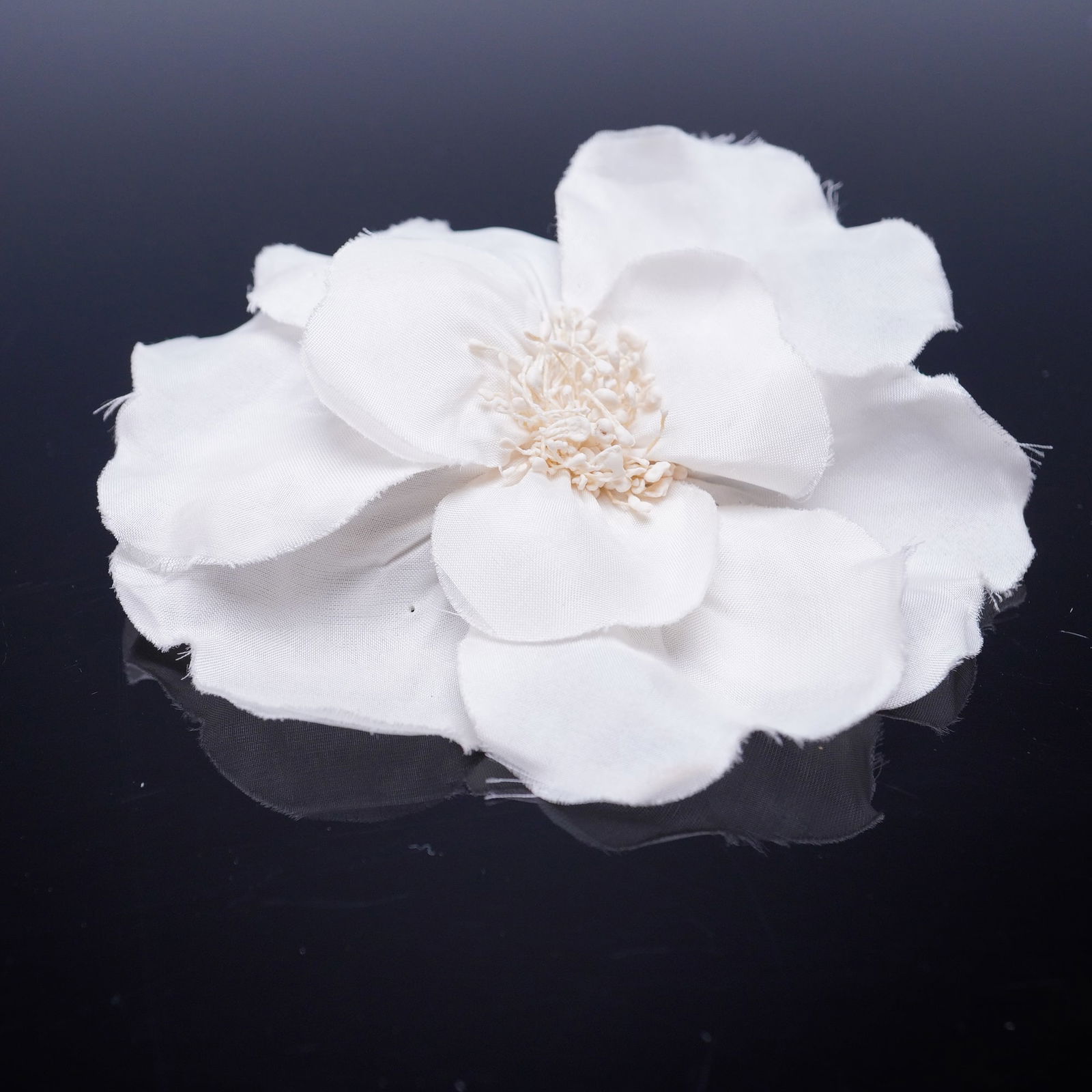 Chanel Paris White Camellia Silk Fabric Brooch Pin: A Chanel Paris camellia silk fabric brooch, crafted in the form of the iconic camellia flower, a signature motif of the luxury house. The accessory features layered white textile petals centered by a