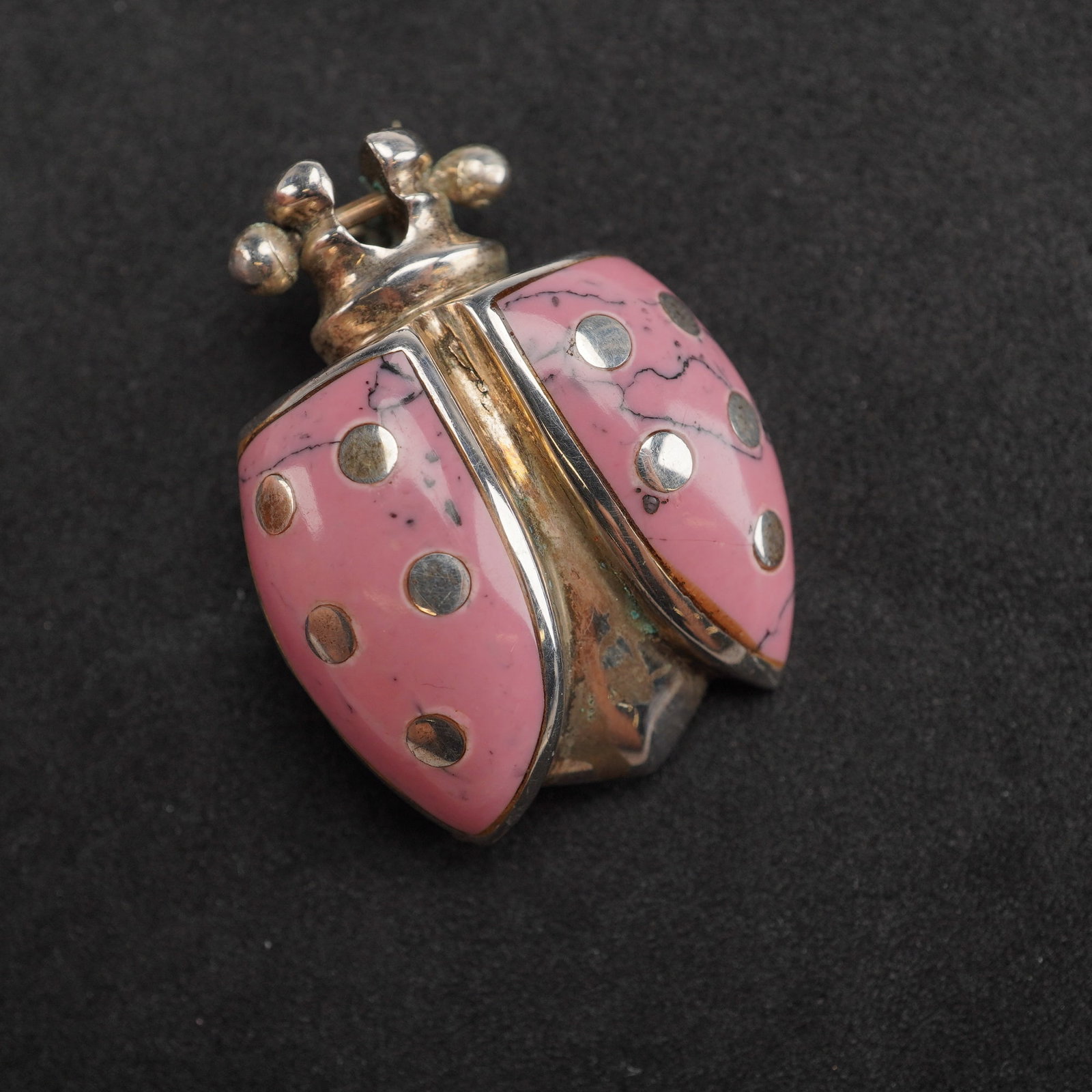 Mexican Sterling Silver and Pink Stone Inlaid Ladybug Brooch: A figural brooch crafted from sterling silver (.925) in the form of a stylized ladybug. This brooch features two wing covers inlaid with a pink composite stone exhibiting distinct black veining. Each