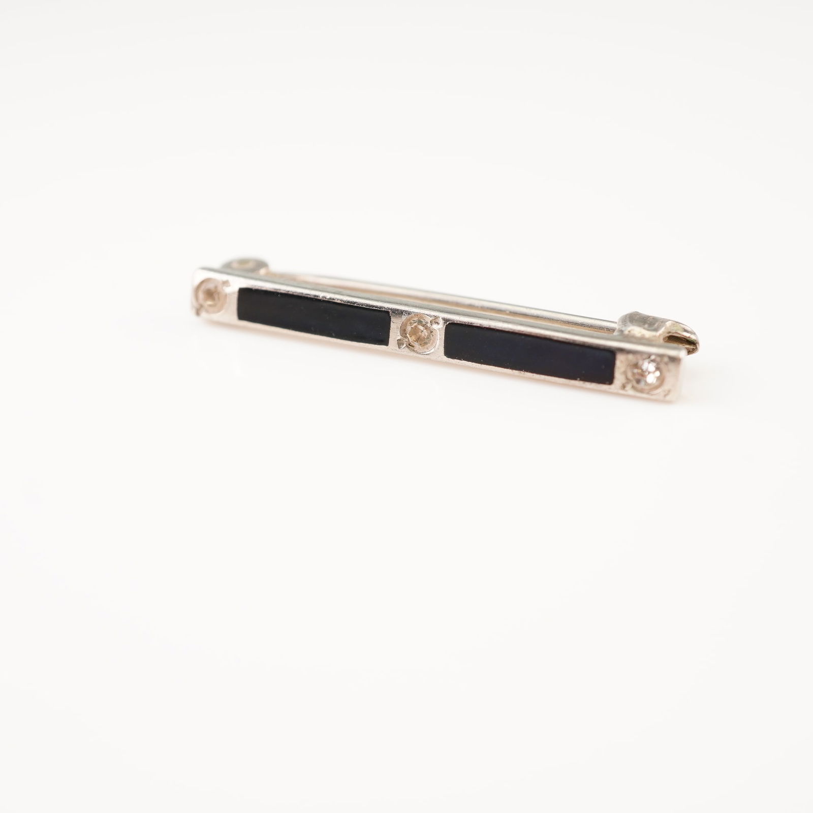Sterling Silver and Onyx Bar Brooch: This vintage bar brooch is crafted from sterling silver and features a classic Art Deco geometric design. The linear arrangement consists of two rectangular black onyx inlays alternating with three sm