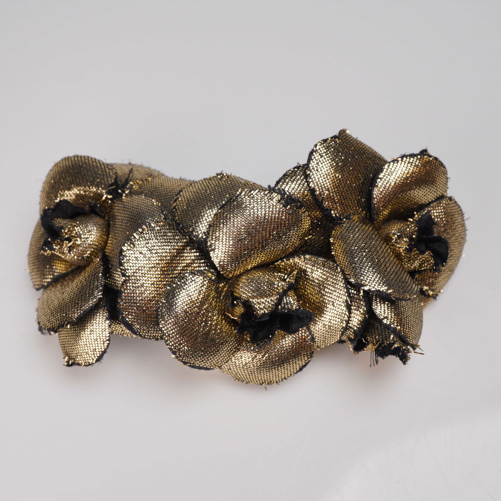 Chanel Paris Metallic Gold Fabric Floral Hair Barrette: A Chanel fabric floral design barrette hair clip that features a cluster of three flowers constructed from a gold-toned metallic woven mesh fabric accented by black threads. The barrette utilizes a si