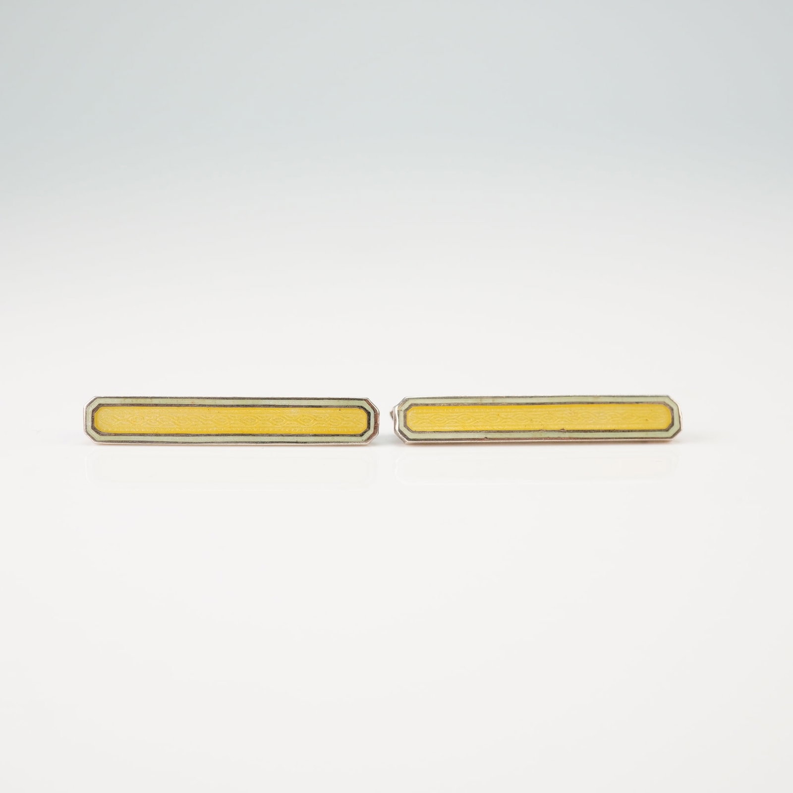 2pc Sterling Silver and Guilloche Enamel Bar Pins: A pair of sterling silver bar brooches featuring clipped corners and soft yellow guilloche enamel. Each pin showcases a central rectangular panel of enamel over an engine-turned pattern, accented by a