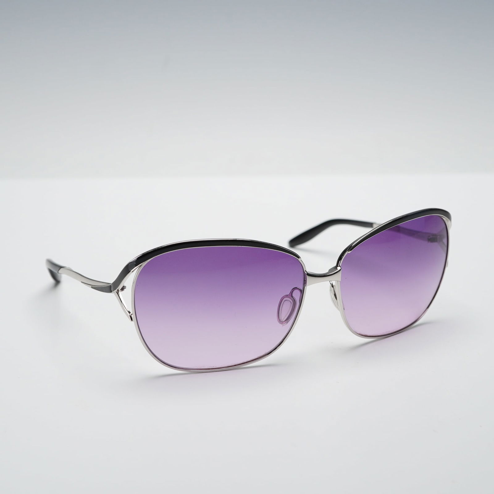 A Pair of Barton Perreira Fair Lady Purple Sunglasses: A pair of Barton Perreira Fair Lady sunglasses with a silver tone metal frame accented by black acetate along the brow line and at the ends, fitted with gradient purple lenses. The left interior templ