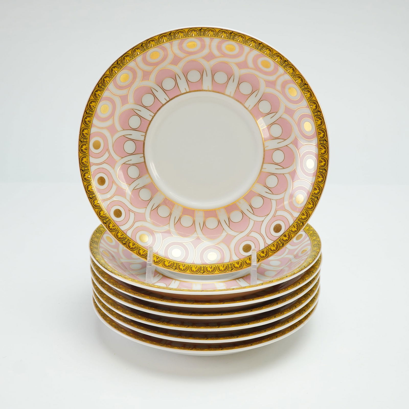 7pc Rosenthal Versace Porcelain Saucers, Les Reves Byzanthins: Each plate features a neoclassical pattern in shades of pink, white, and gold. The design is bordered by an architectural geometric band in gold with additional banding in pink and white. The reverse