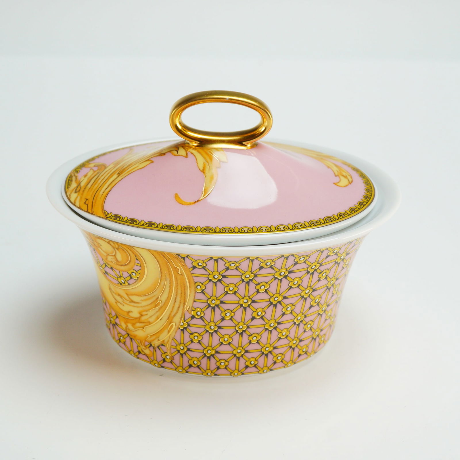 Versace Rosenthal Porcelain Lidded Sugar Bowl, Les Reves Byzantins: The vessel is constructed with an oval, flared body and a coordinating domed lid featuring a gold-toned ring handle. The exterior decoration consists of an intricate gold-toned geometric lattice patte