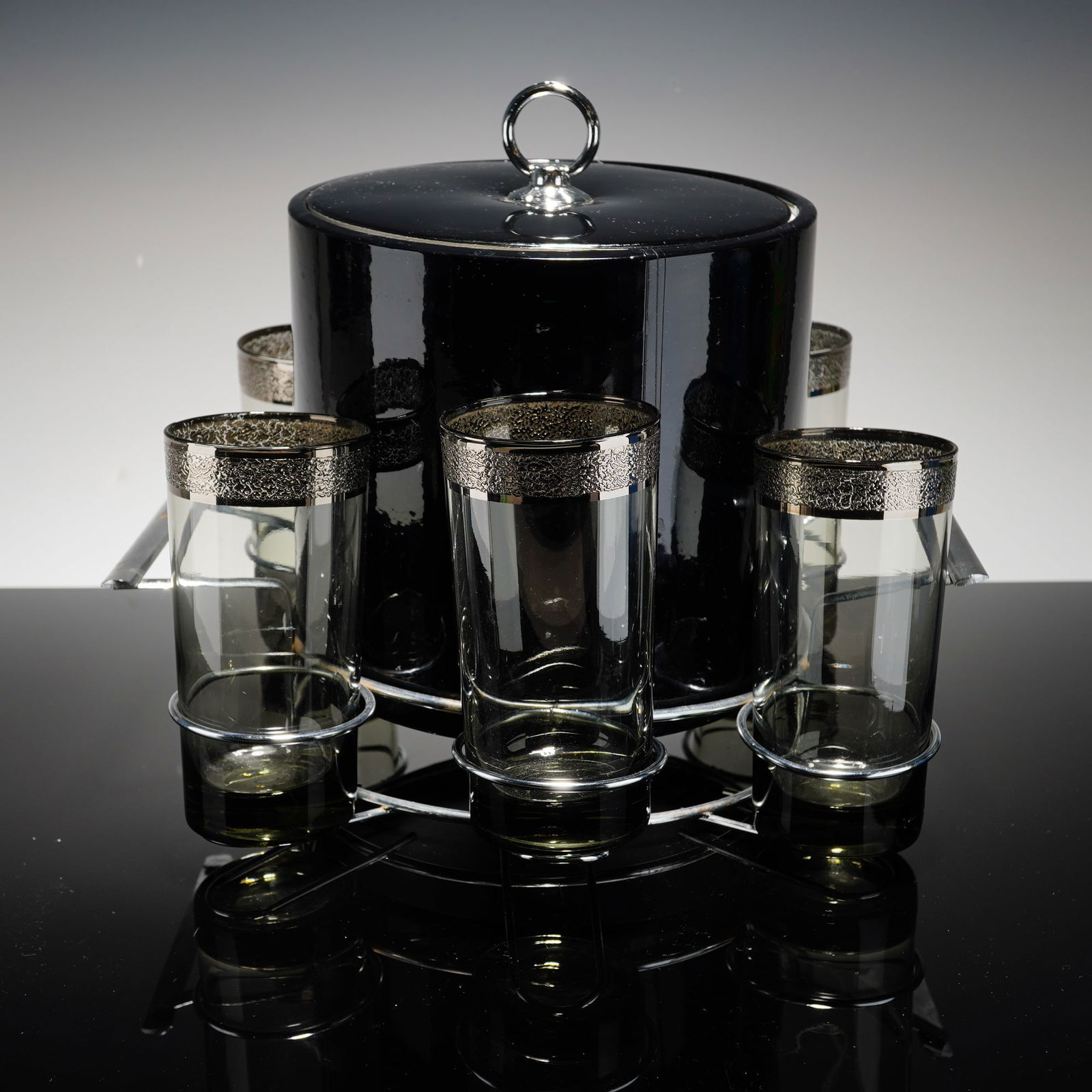 8pc Vitreon Queen's Lusterware Mid-Century Modern Silver Fade Barware Set: The set includes six tall tumblers crafted from smoky gray glass, each accented with a wide, textured silver-toned band at the rim. The coordinating circular ice bucket is lidded and insulated, design