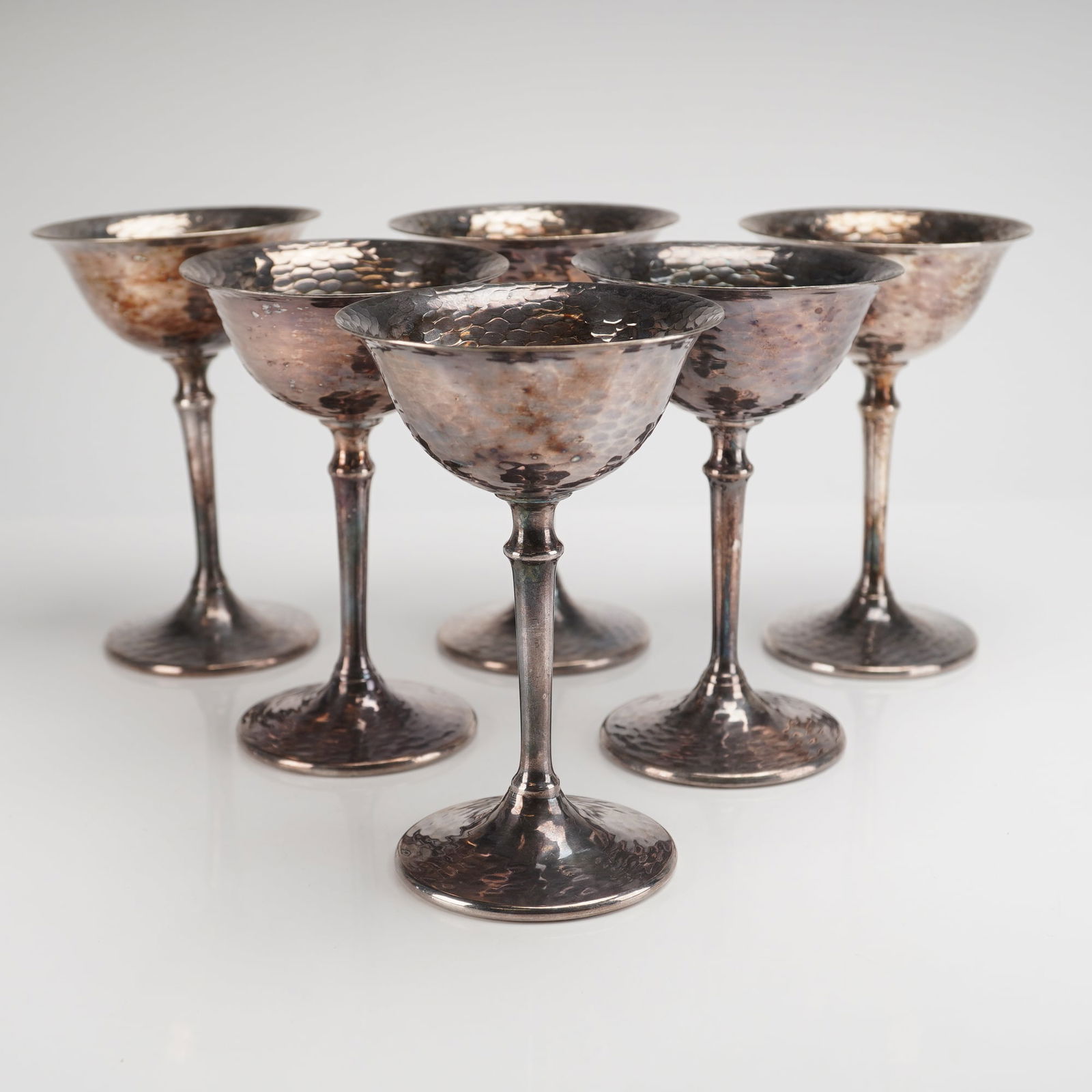 6pc Wallace Nickle Silver Hammered Dimple Coupes: A collection of six stemmed drinking vessels, identified as goblets or large cordials, manufactured by Wallace. The set is executed in silver-plated metal over a nickel silver (NS) base. The form feat